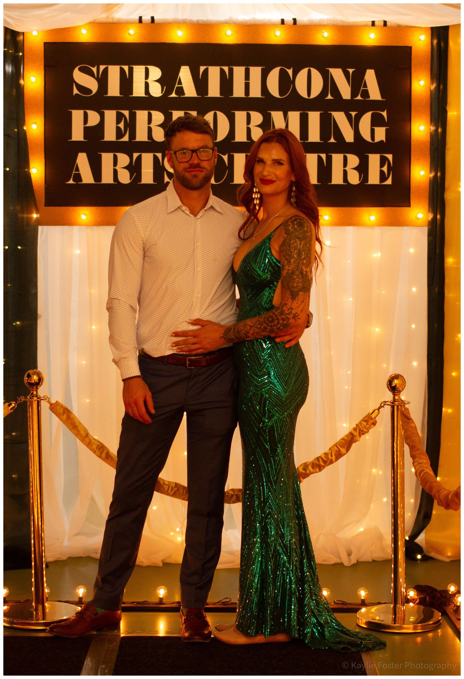 Couple posing in front of the Strathcona Performing Arts Centre marquee sign at a formal event.