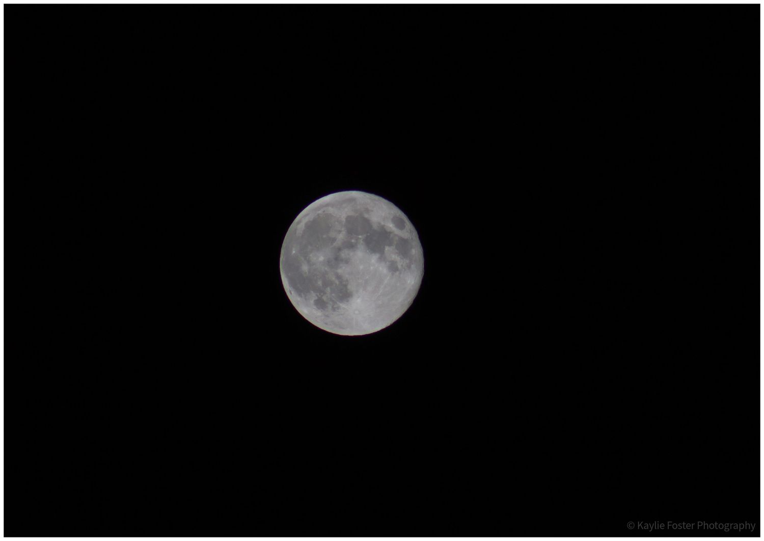 Detailed full moon photograph against a pitch black night sky showing lunar surface craters and features.