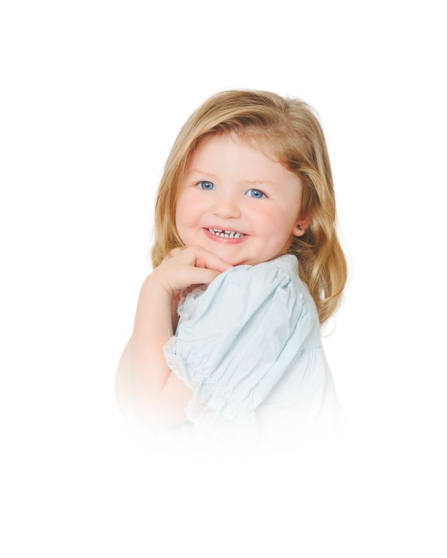Smiling toddler girl with blue eyes and blonde hair wearing a light blue top, posing cheerfully against white background.