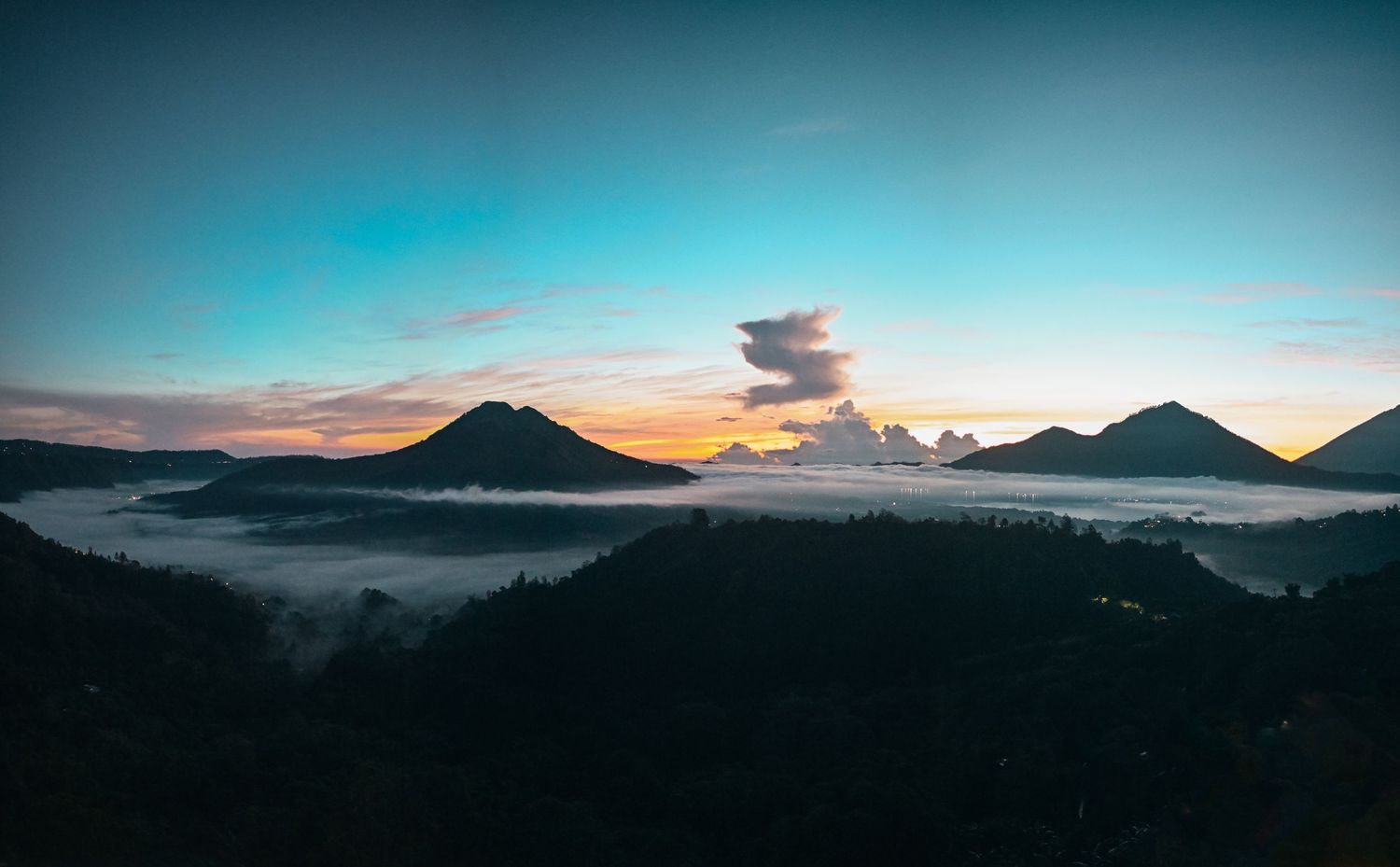 Panoramic sunrise view of misty volcanic mountains with colorful sky in Bali, Indonesia.