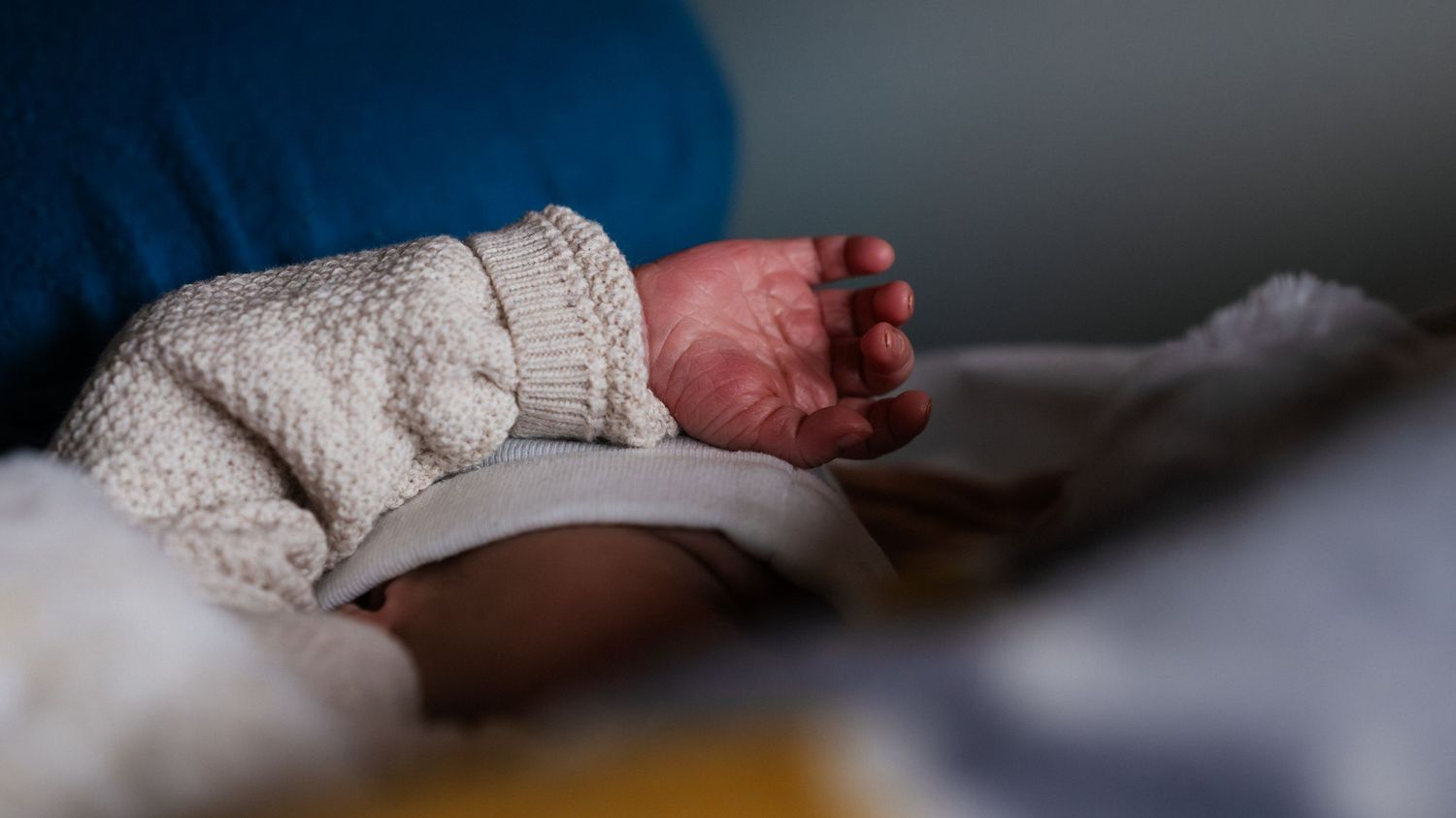 Close-up of a newborn baby's tiny feet wrapped in a soft white knit blanket.