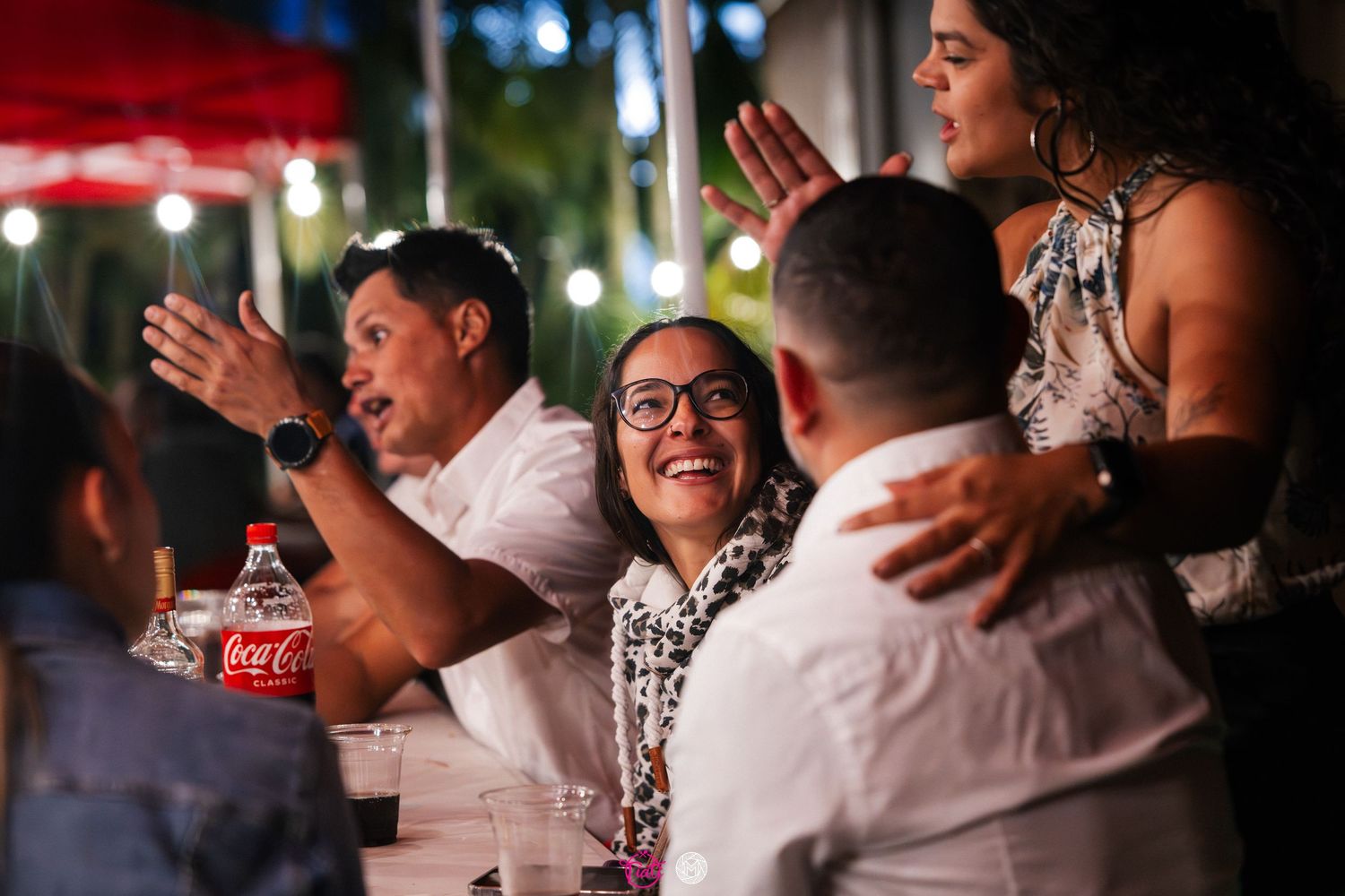 Group of friends laughing and enjoying themselves at an outdoor nighttime dinner party.