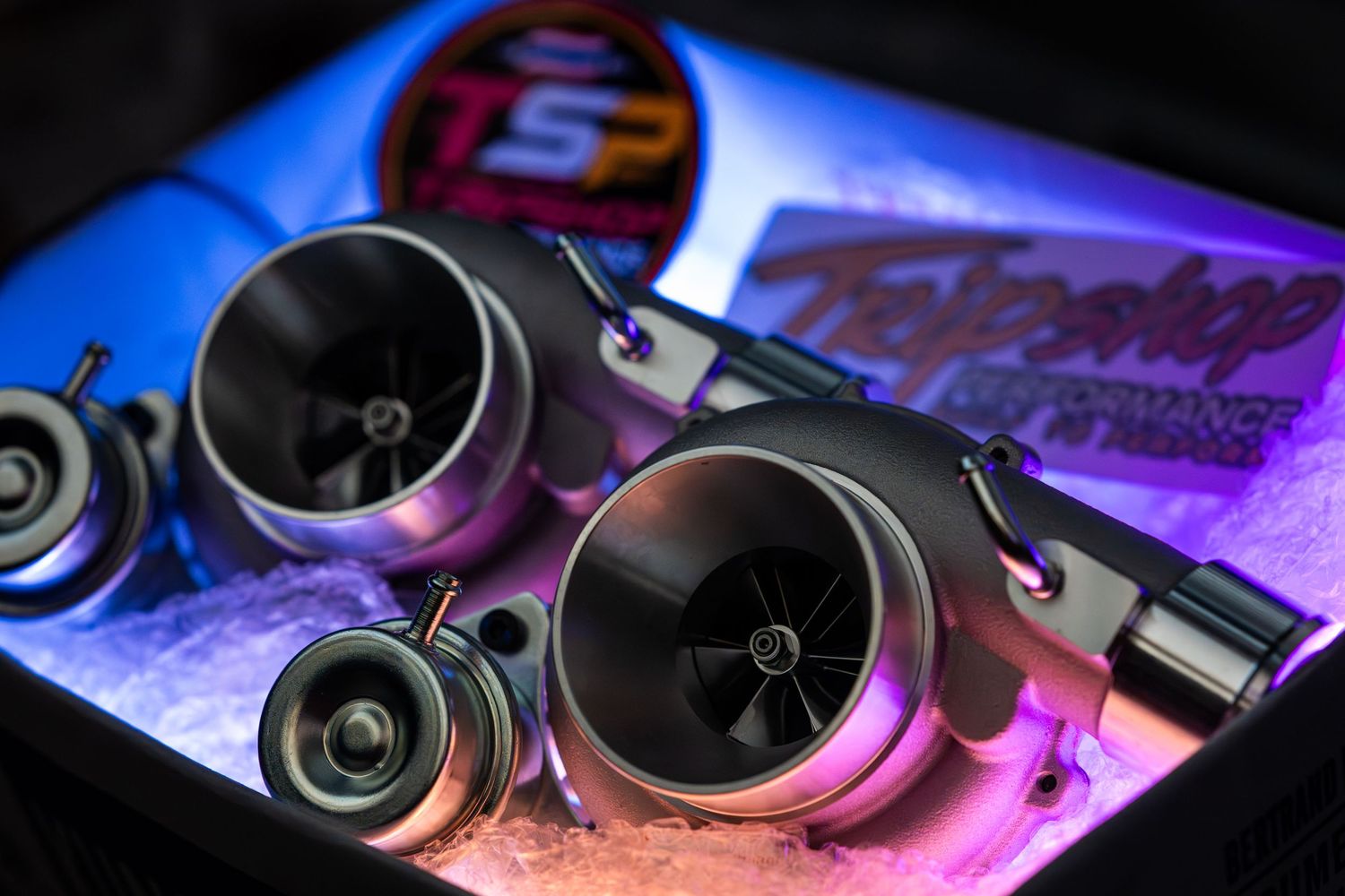 Close-up of turbochargers displayed in illuminated case with colorful purple and blue lighting.