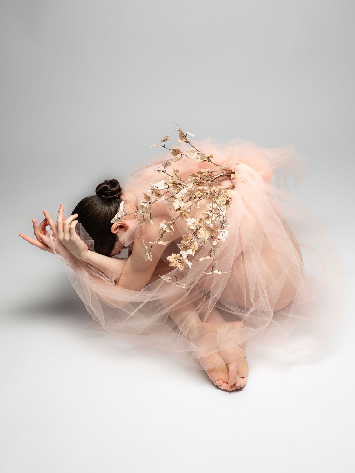 Ballerina in pink tulle gown with gold floral details in graceful crouching pose.
