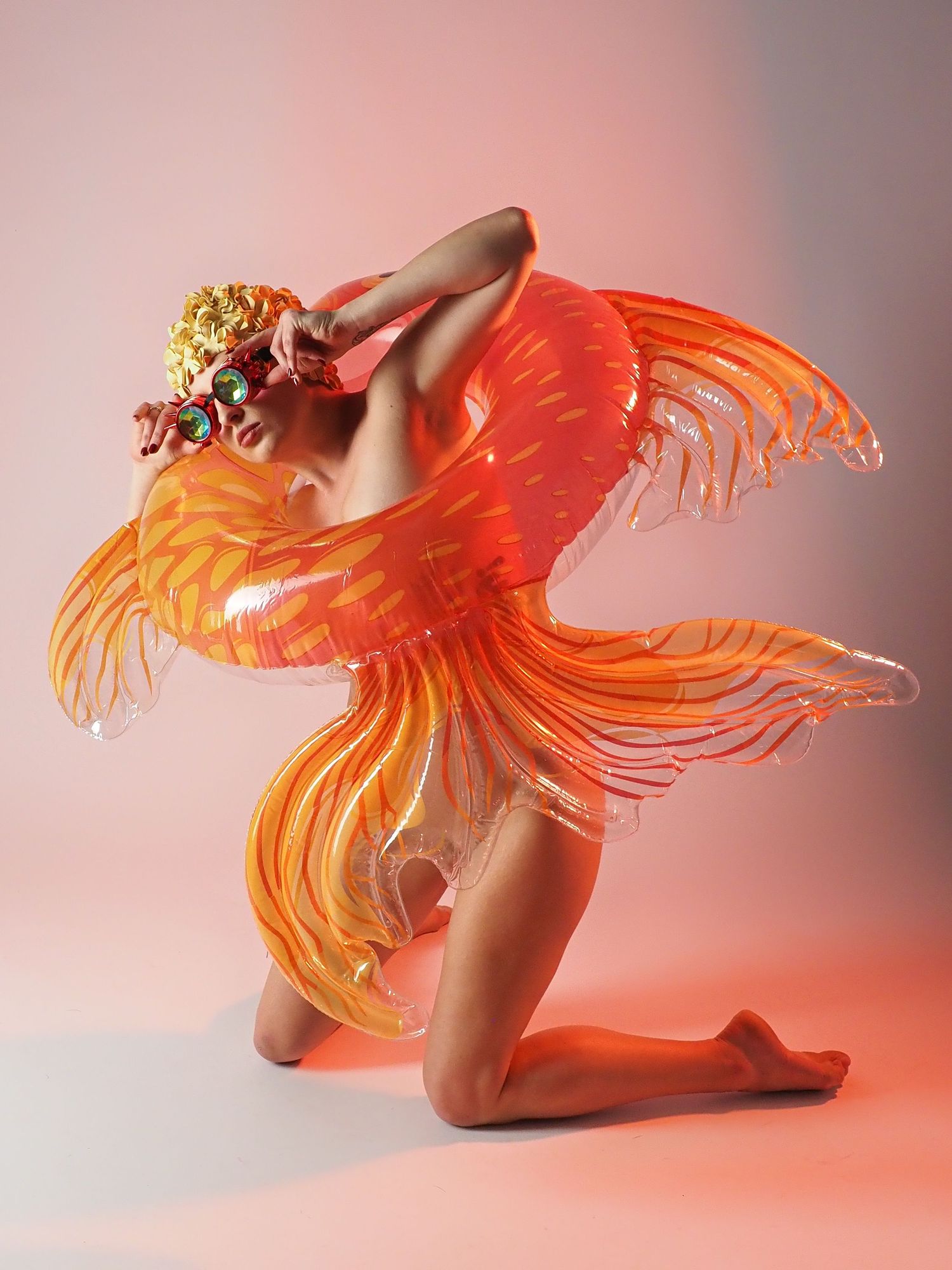 Dynamic fine art photo of model wearing vibrant orange translucent wing costume in studio.
