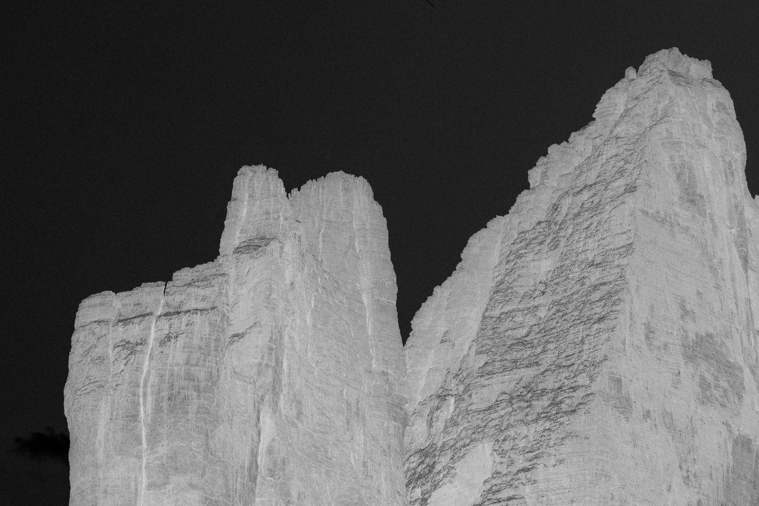 Black and white dramatic close-up of towering white rock formations against a dark sky.