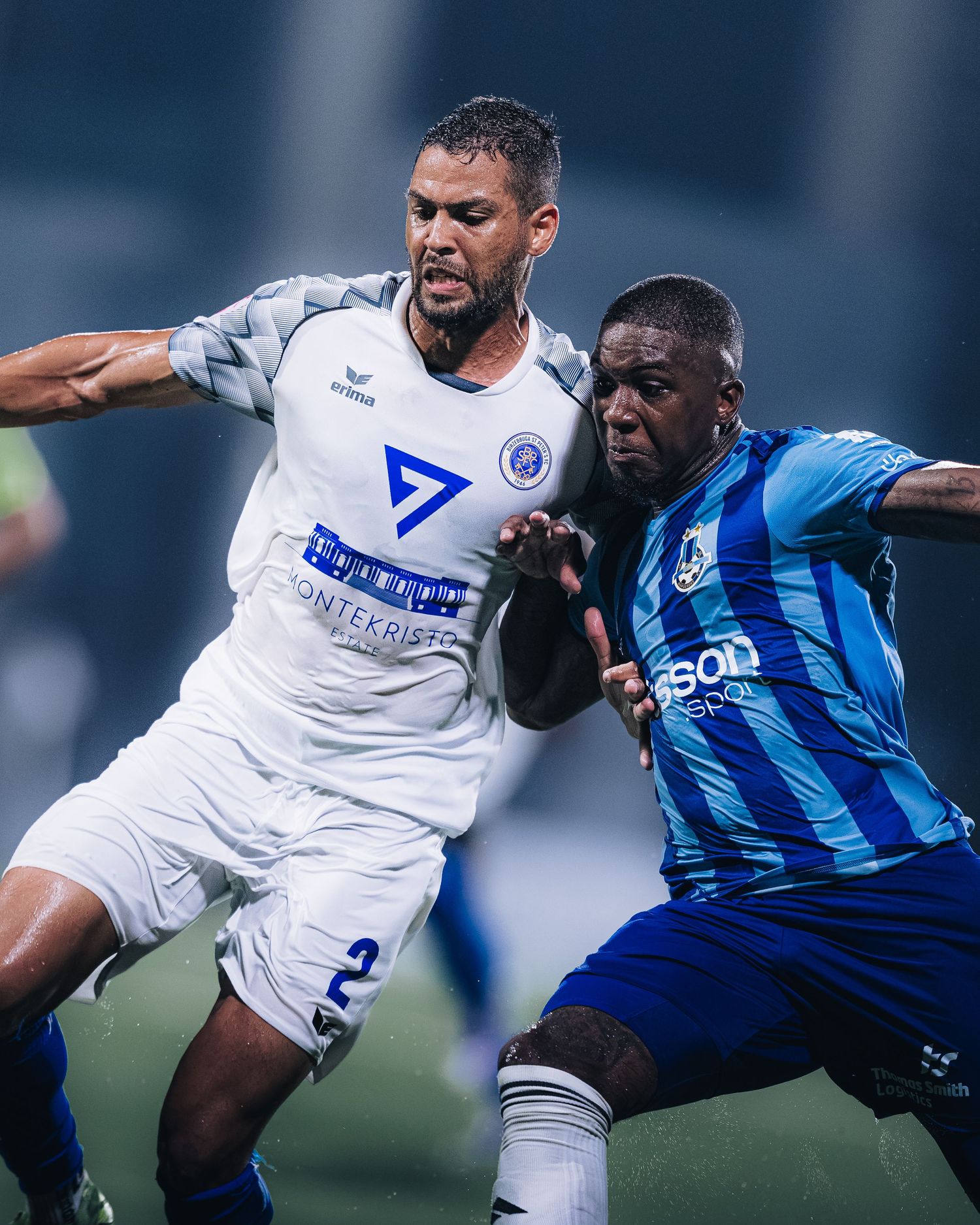 Two soccer players battle for ball during competitive match.