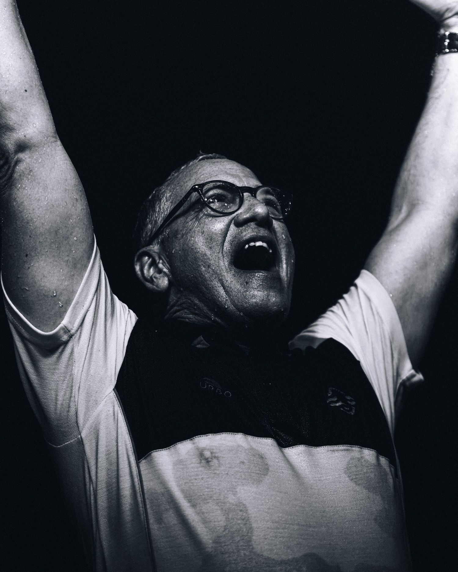 Man celebrating victory with arms raised and mouth open in black and white photo.