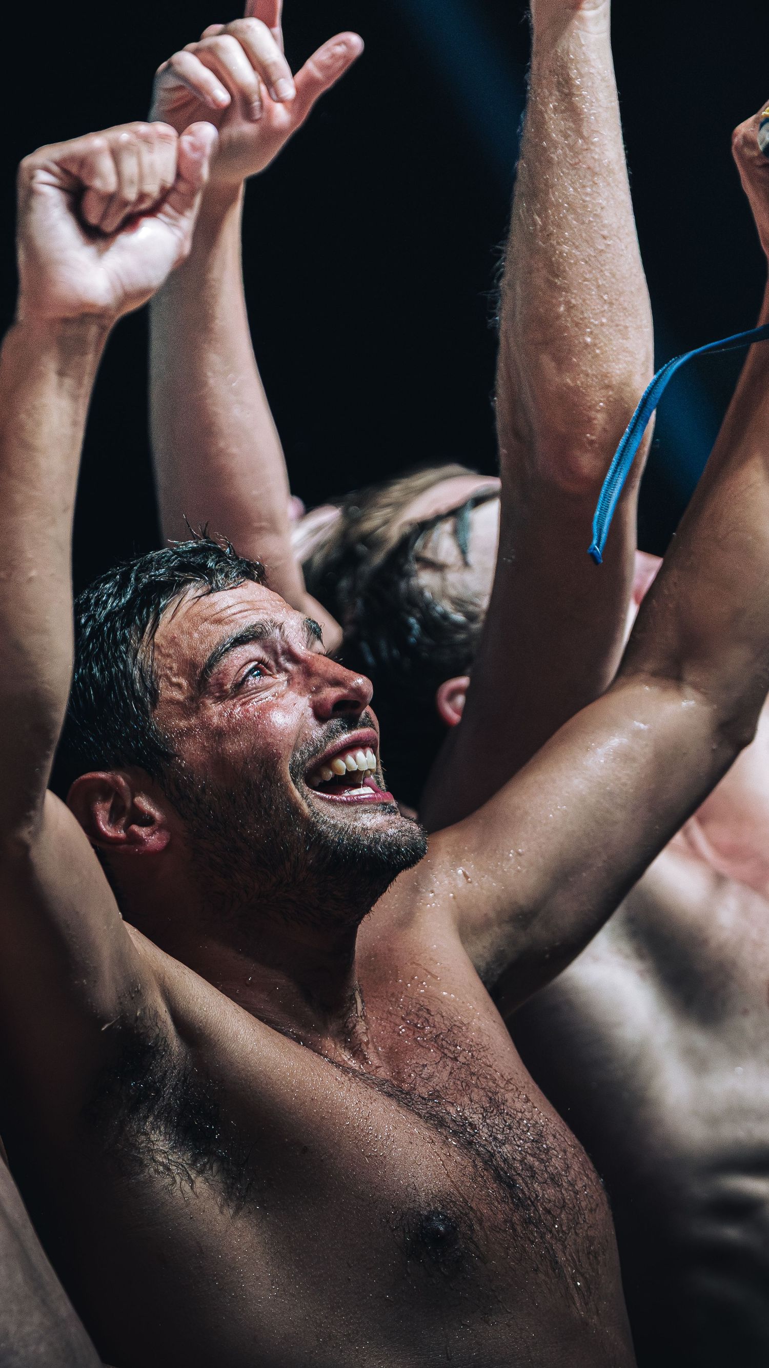 Emotional water polo player celebrating victory with arms raised after championship win.