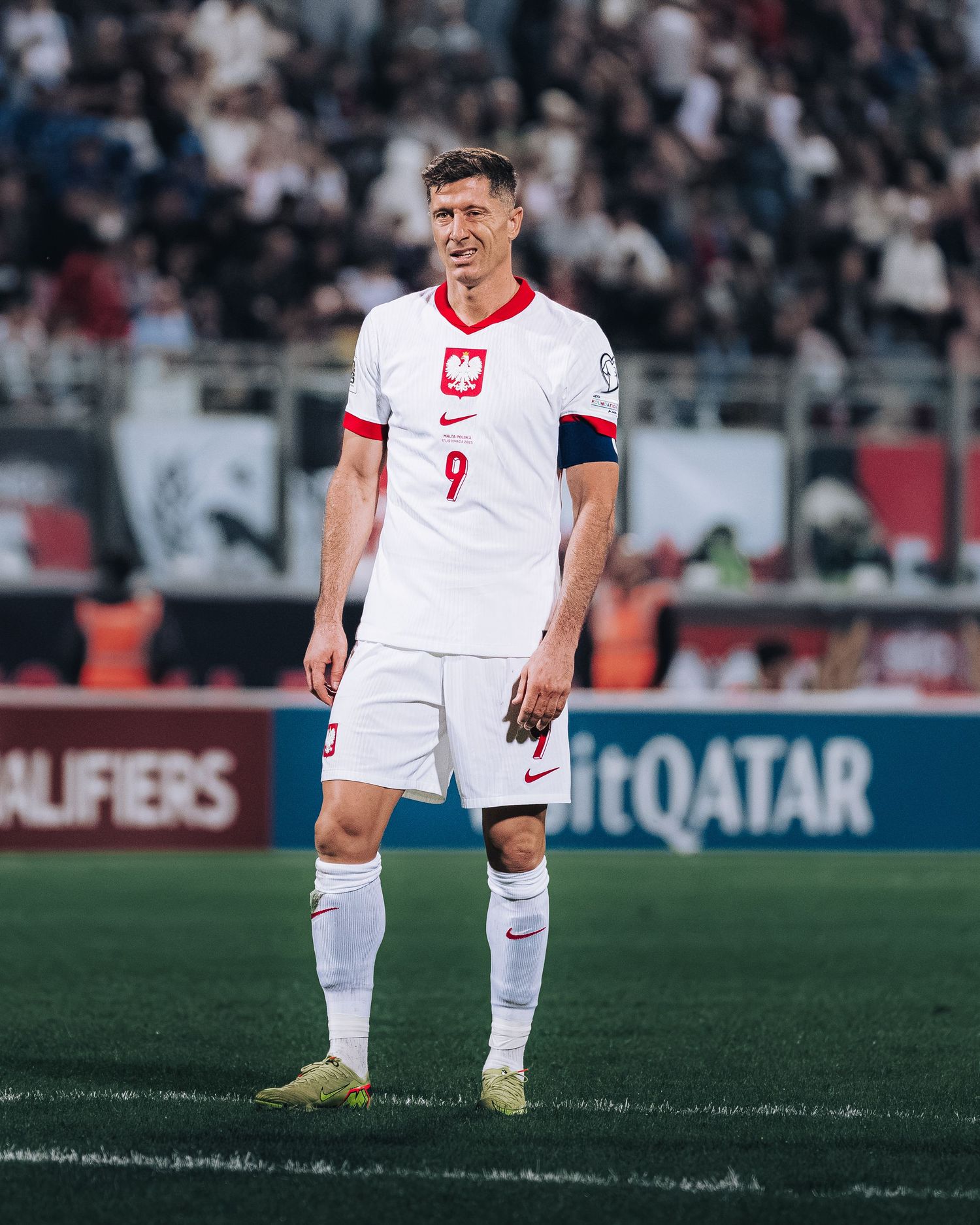 Poland footballer wearing number 9 white Nike kit smiling during a FIFA World Cup qualifier match.