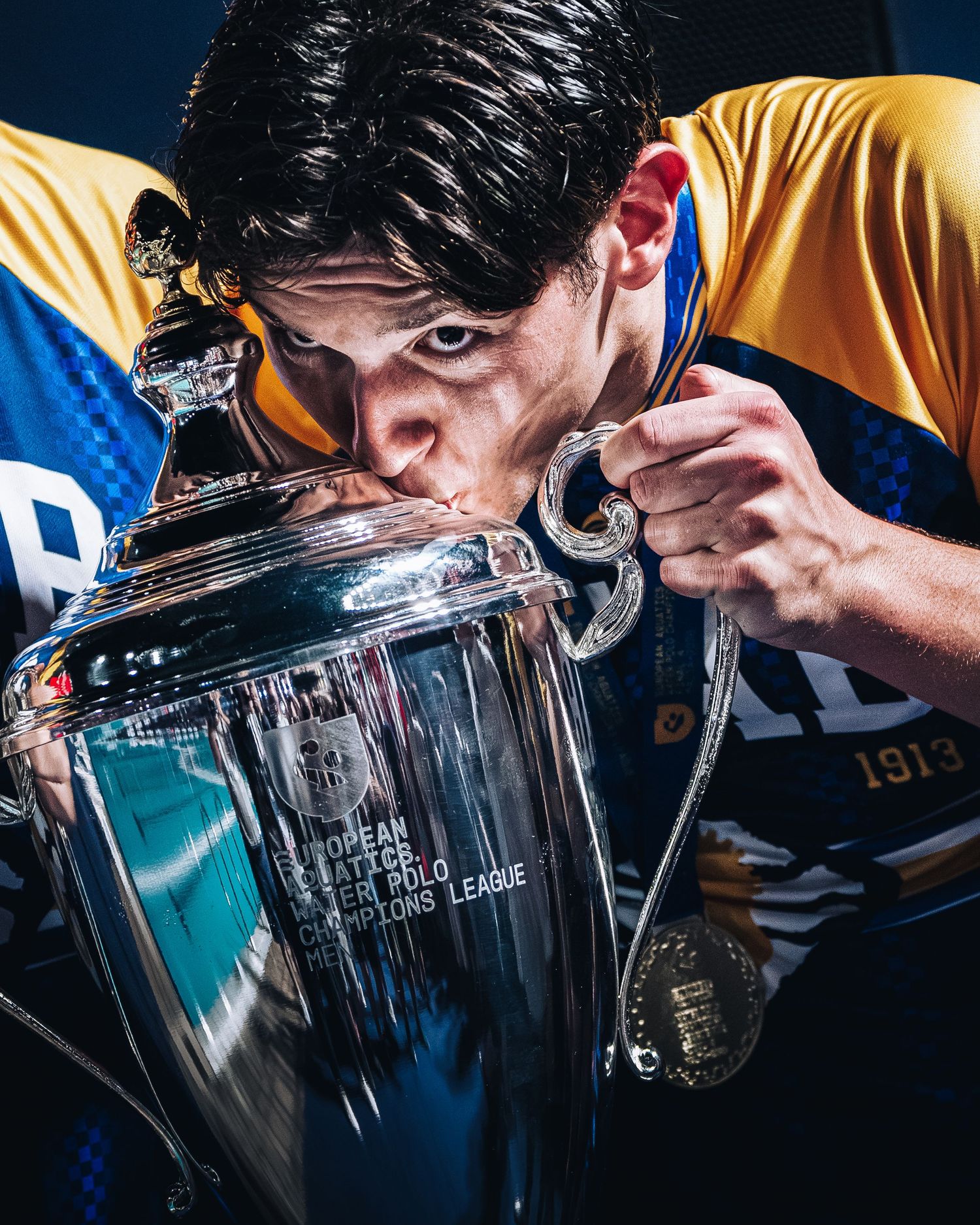Water polo player kissing the European Water Polo Champions League trophy.