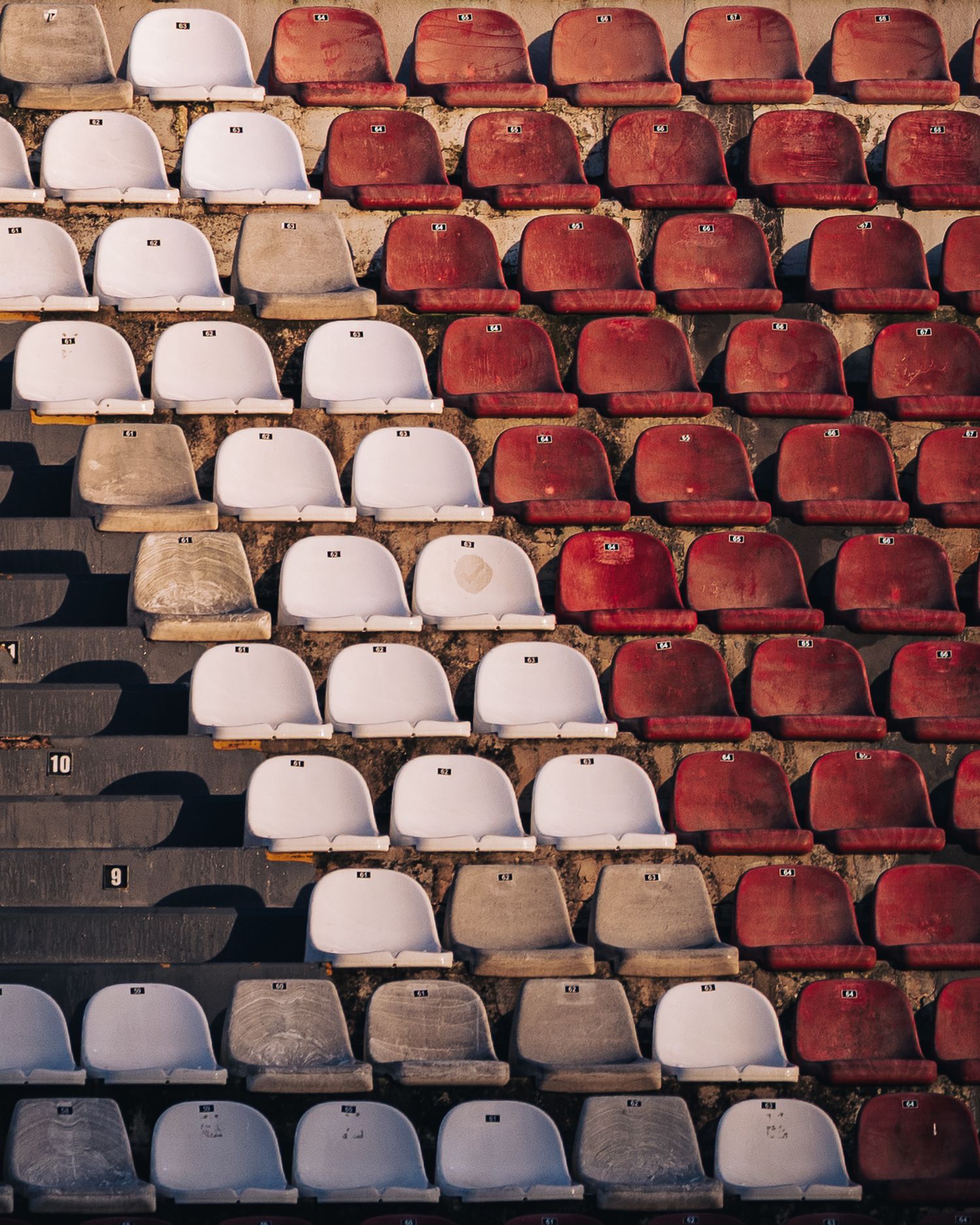 Empty stadium seating in red and white colors arranged in rows at a sports venue.