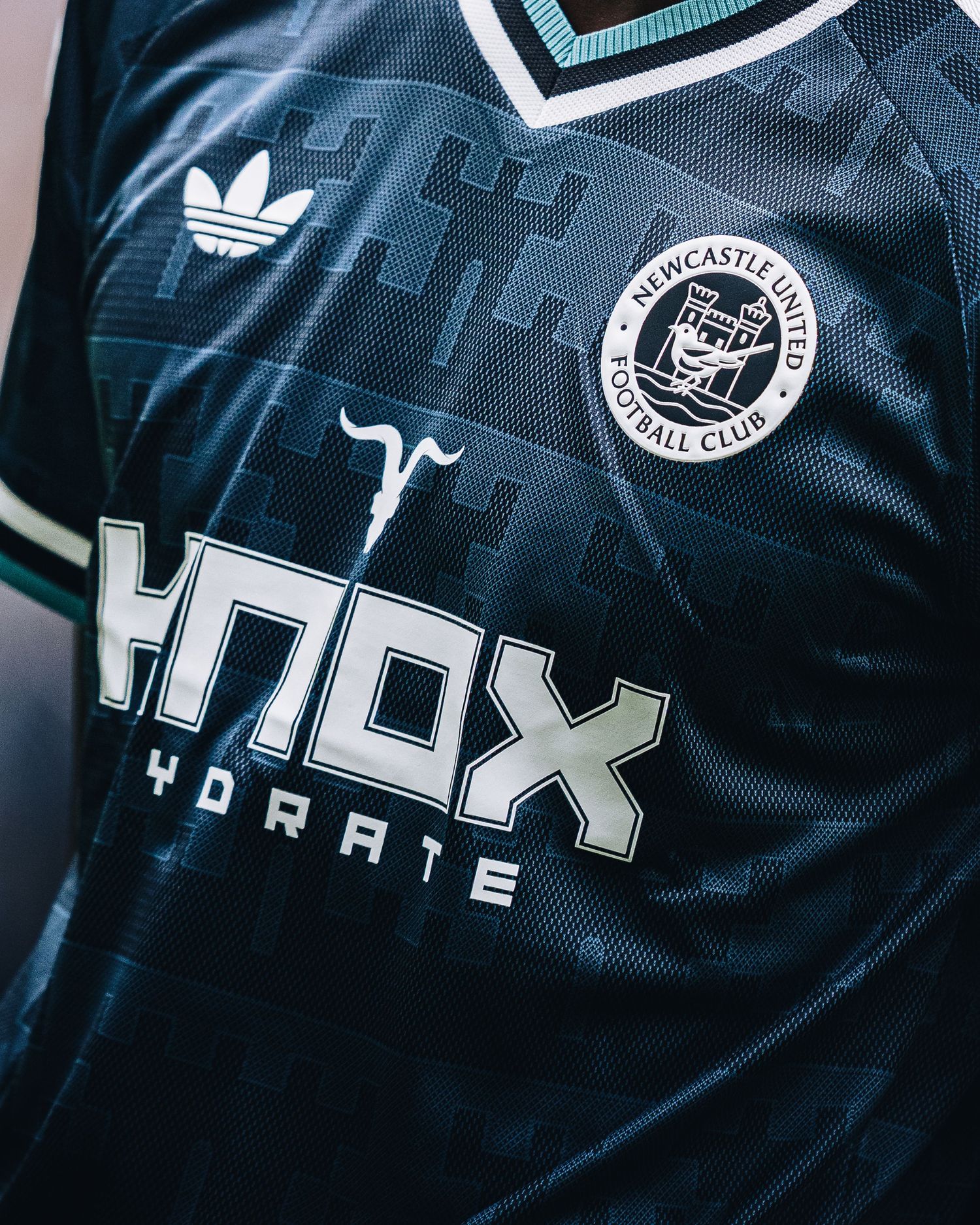 Newcastle United dark Adidas jersey with Knox Hydrate sponsor displayed close-up.