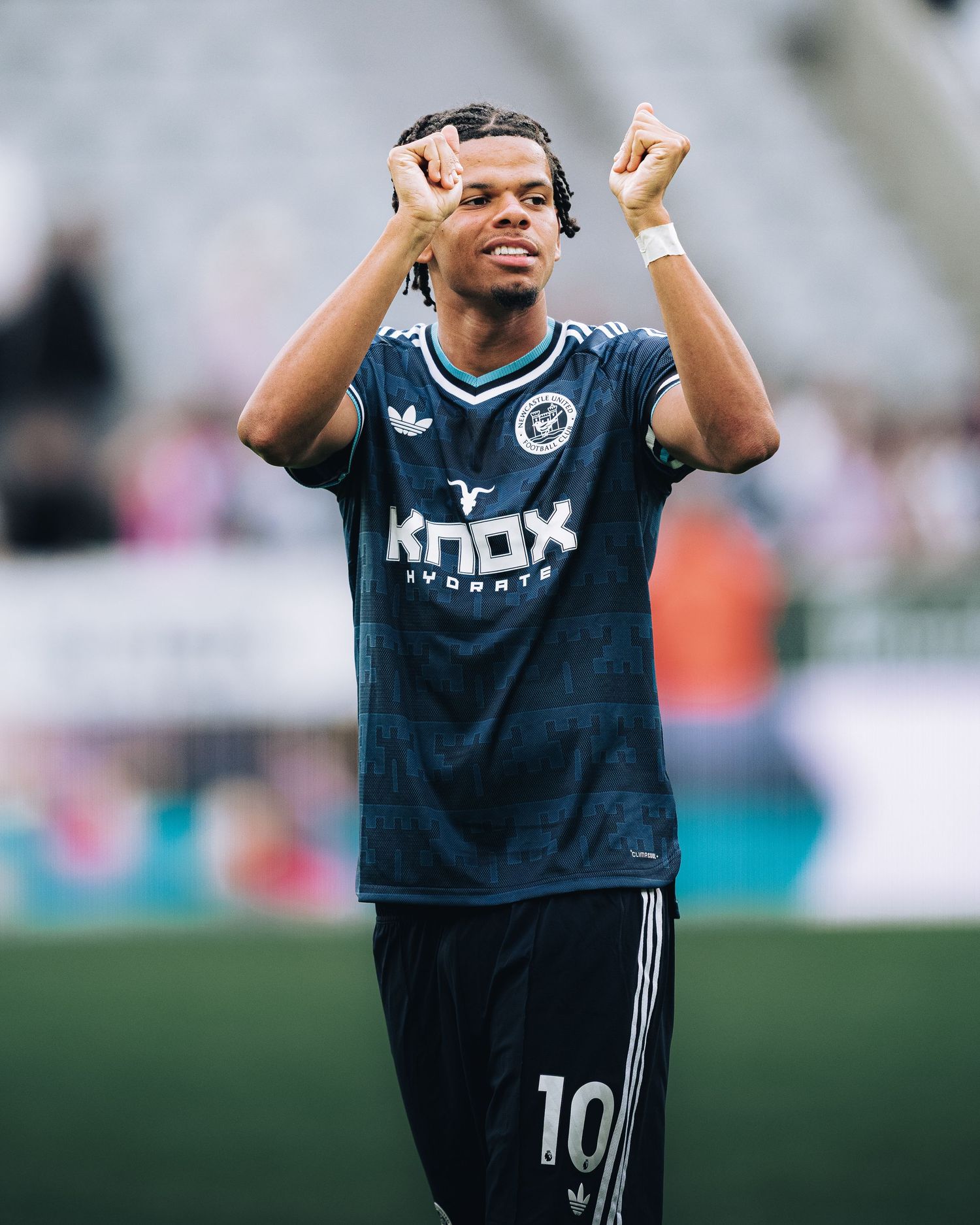 Soccer player wearing number 10 Knox Hydrate jersey raises fists in celebration on the field.