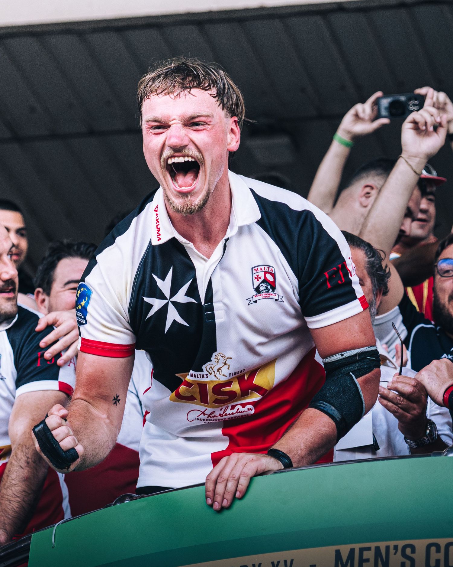 Ecstatic rugby player in black and white jersey celebrates a championship win with fans.