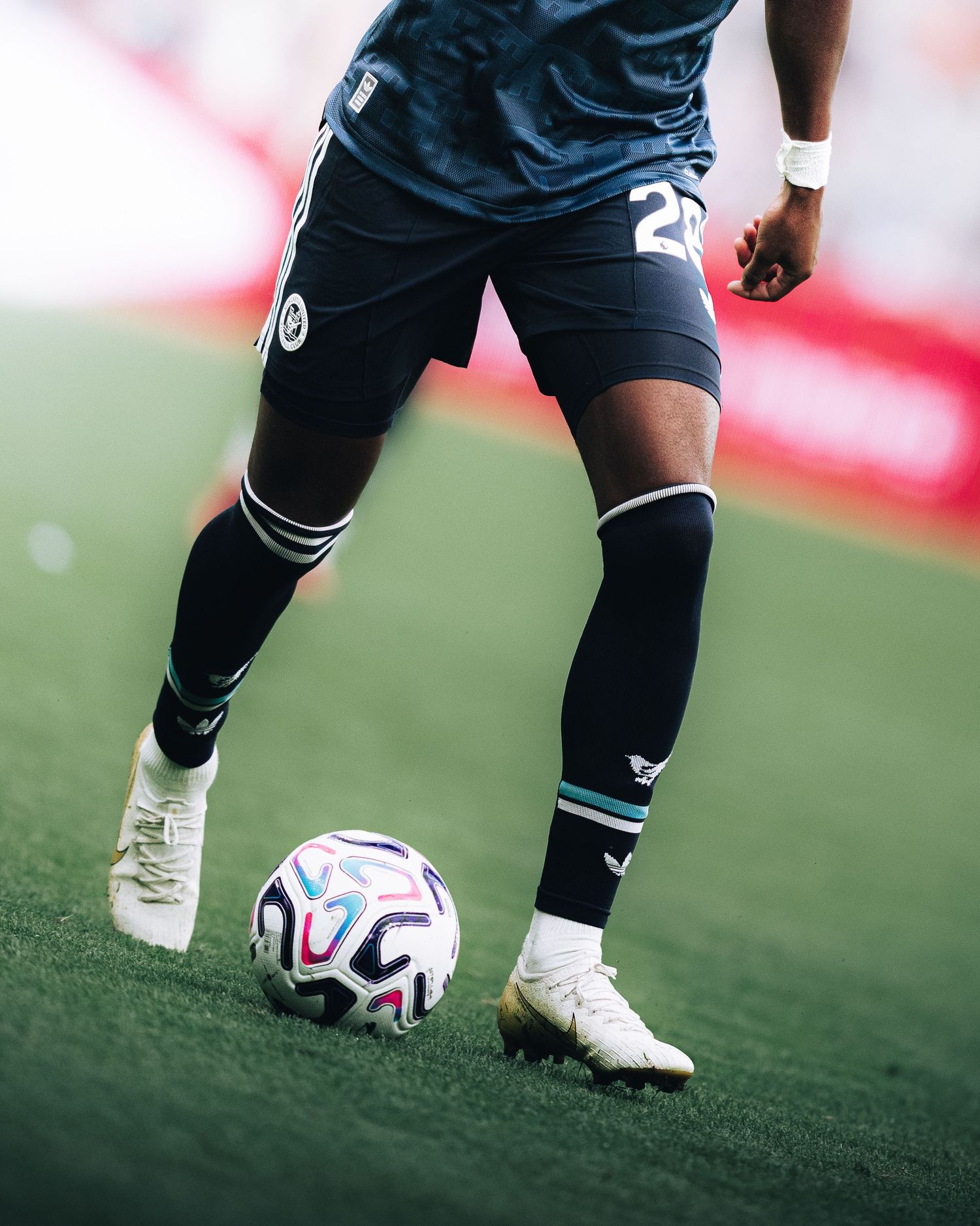 Close-up of footballer in dark kit number 21 controlling ball on grass.
