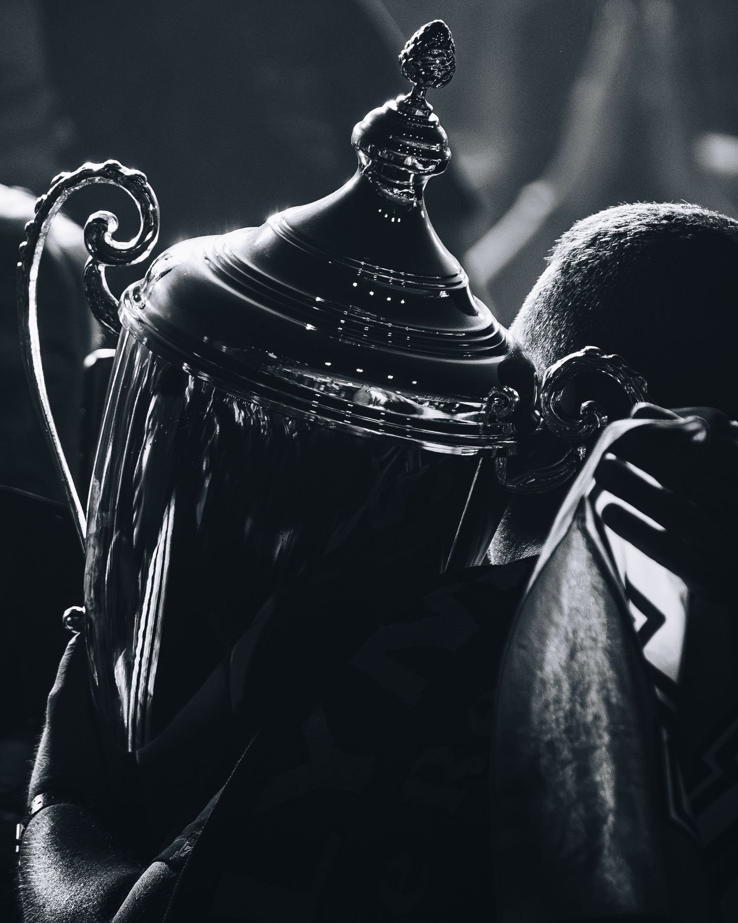 Black and white close-up of an ornate sports trophy being held by an athlete.