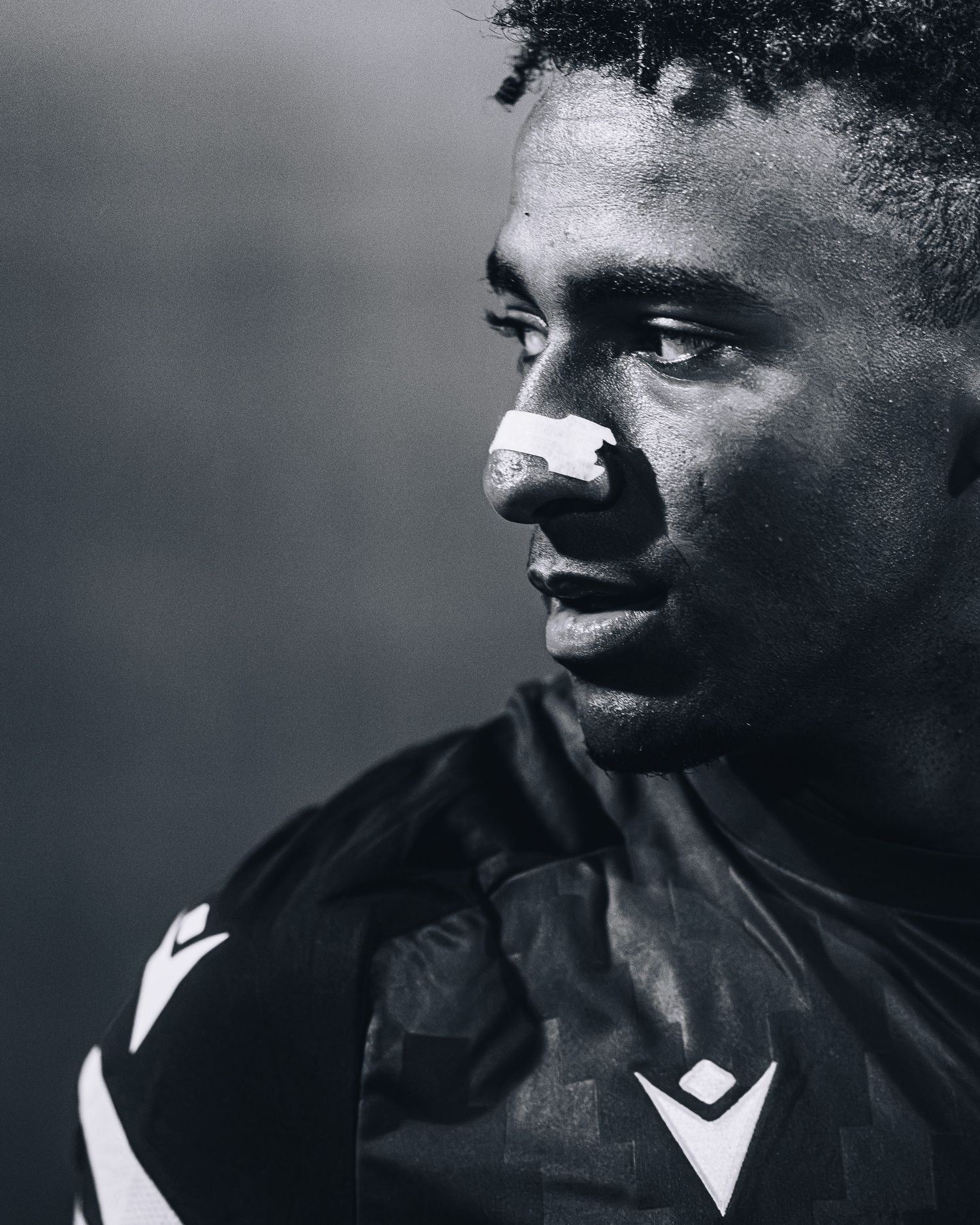 Black and white portrait of soccer player with nose bandage.