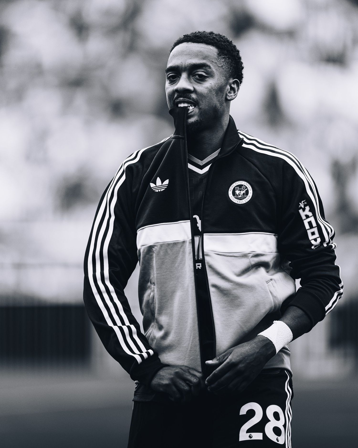 Black and white photo of footballer in Adidas tracksuit number 28 on pitch.