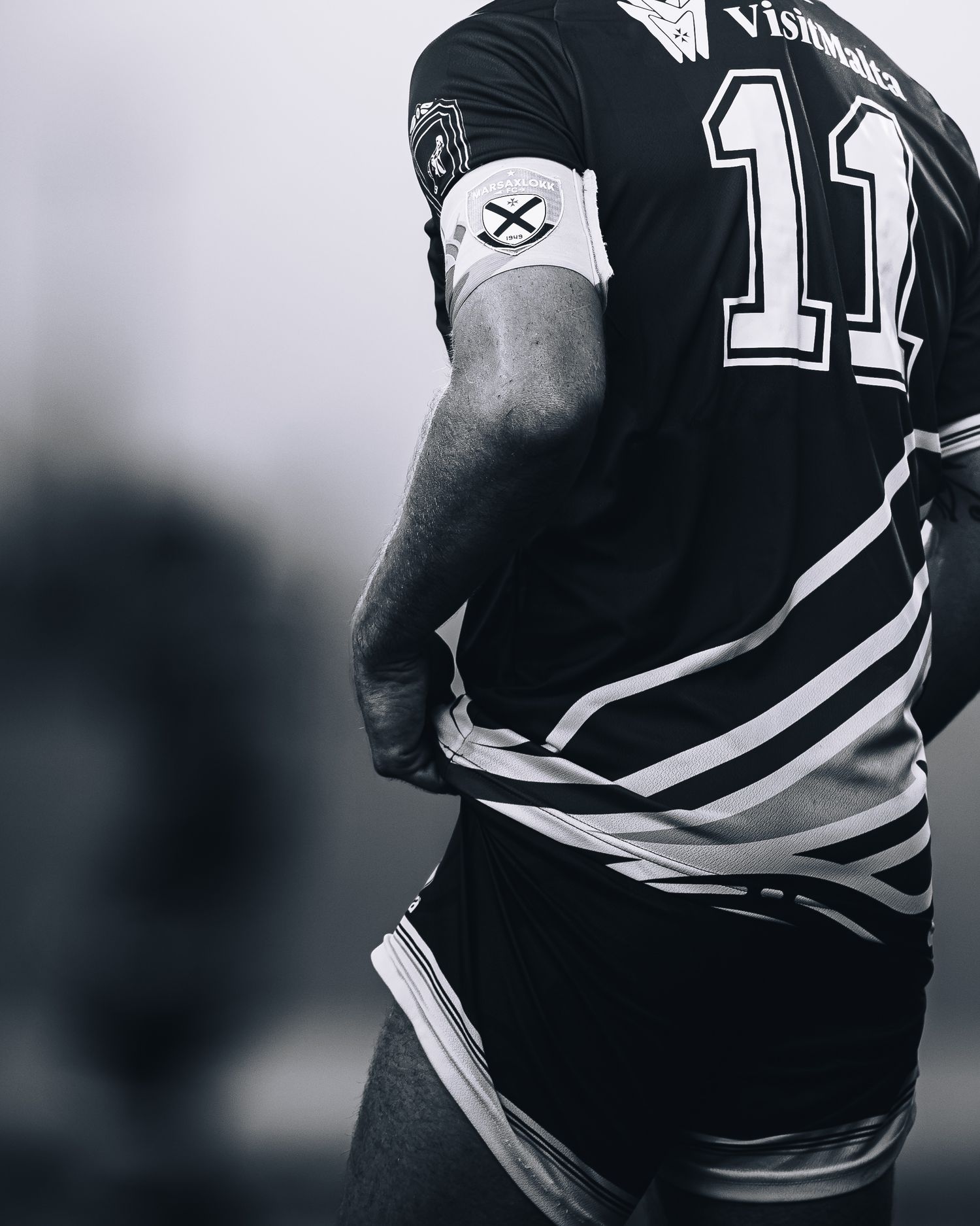 Back view of athlete wearing black number 11 jersey in dramatic black and white sports photo.