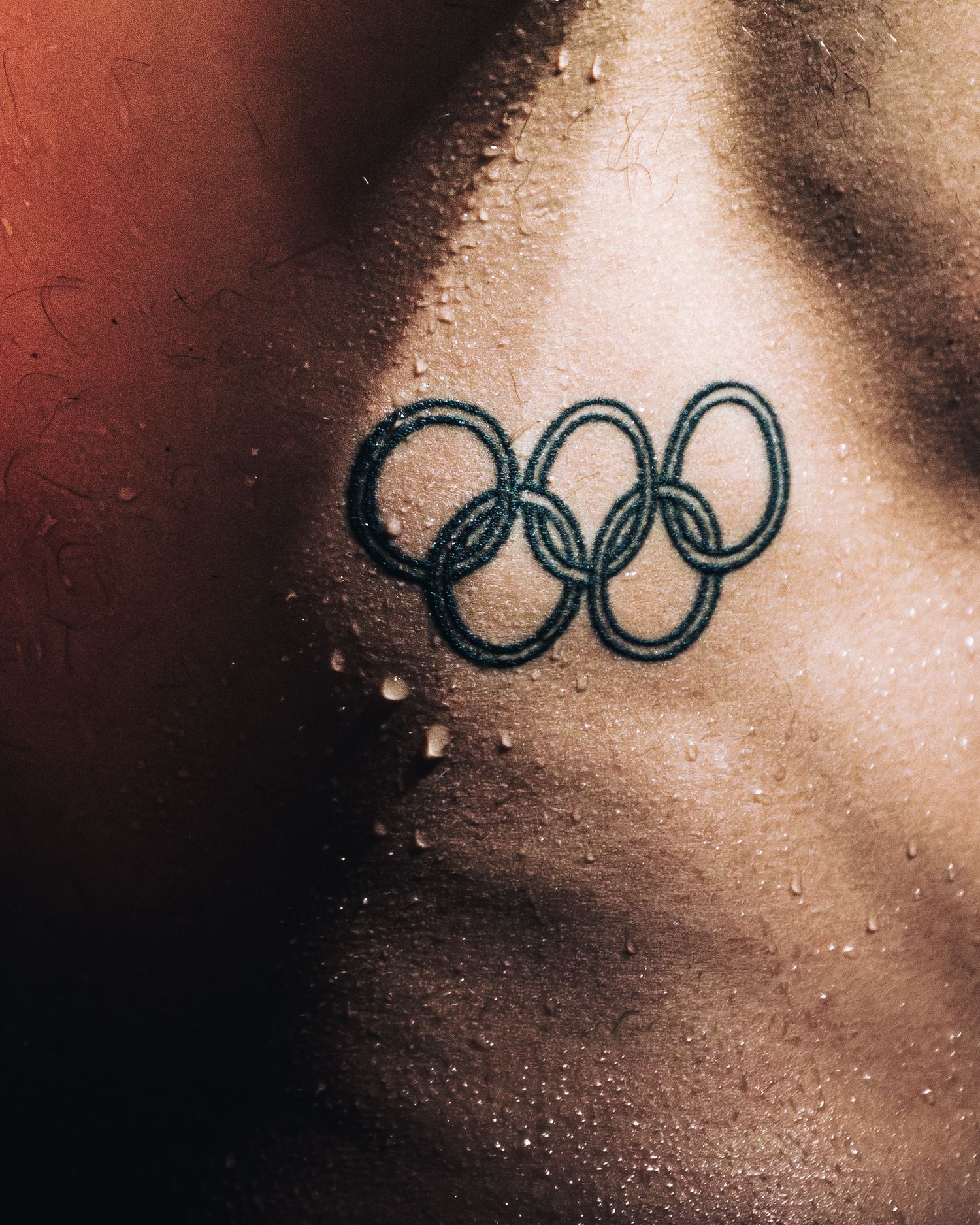 Olympic rings tattoo on athlete's wet skin close-up detail shot.