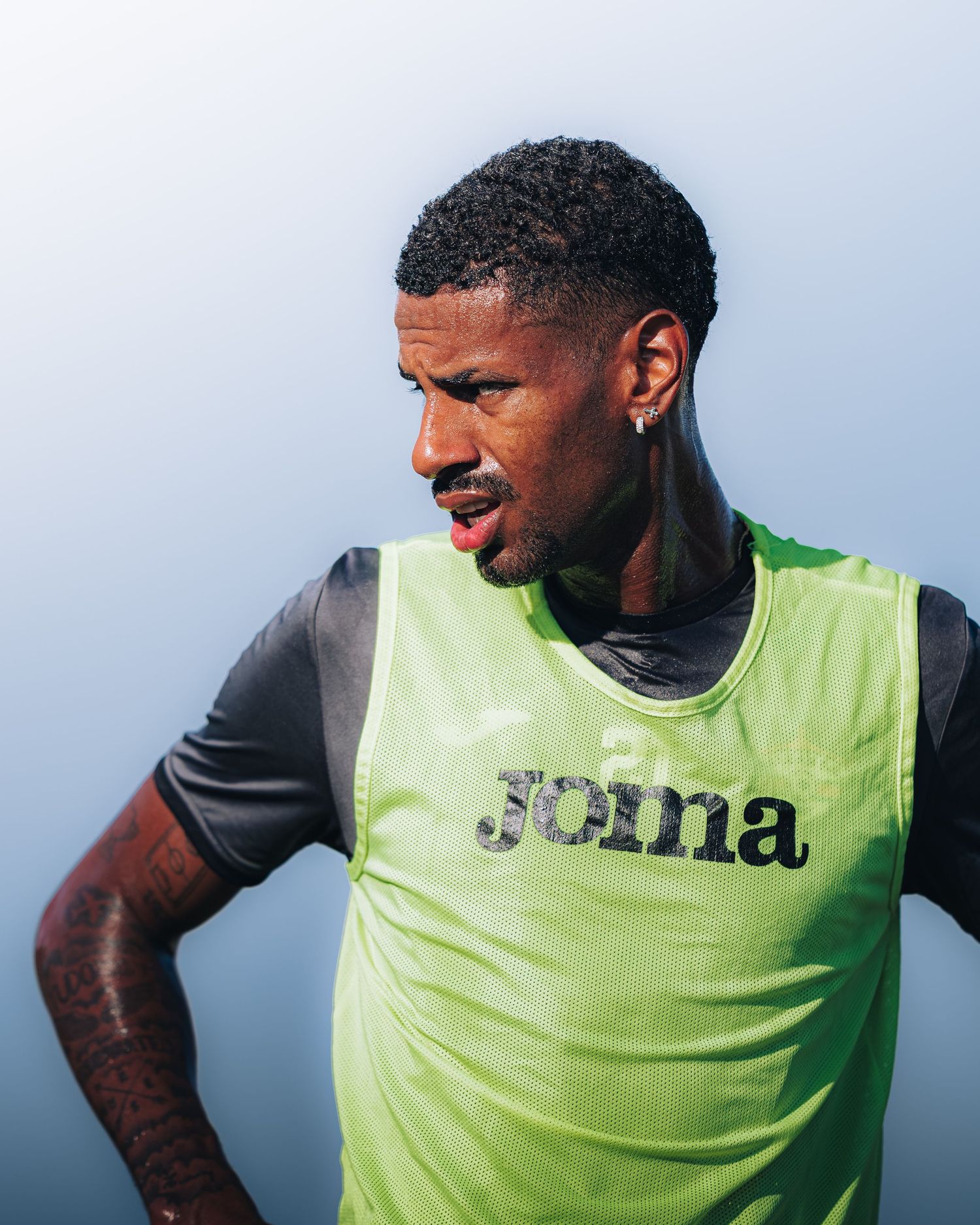 Soccer player wearing green Joma training bib during practice session.