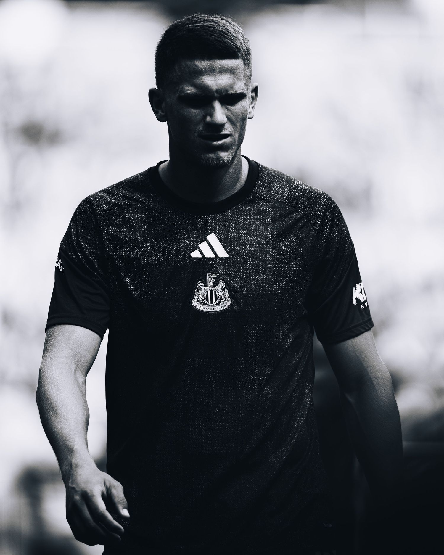Black and white portrait of Newcastle United player in Adidas training shirt pre-match.