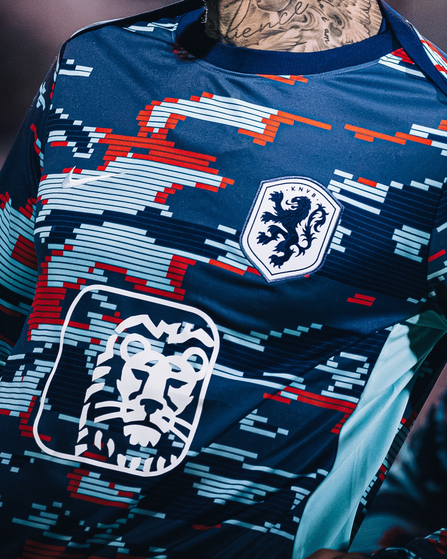 Close-up of navy blue patterned soccer jersey with lion crest badge and red geometric design.