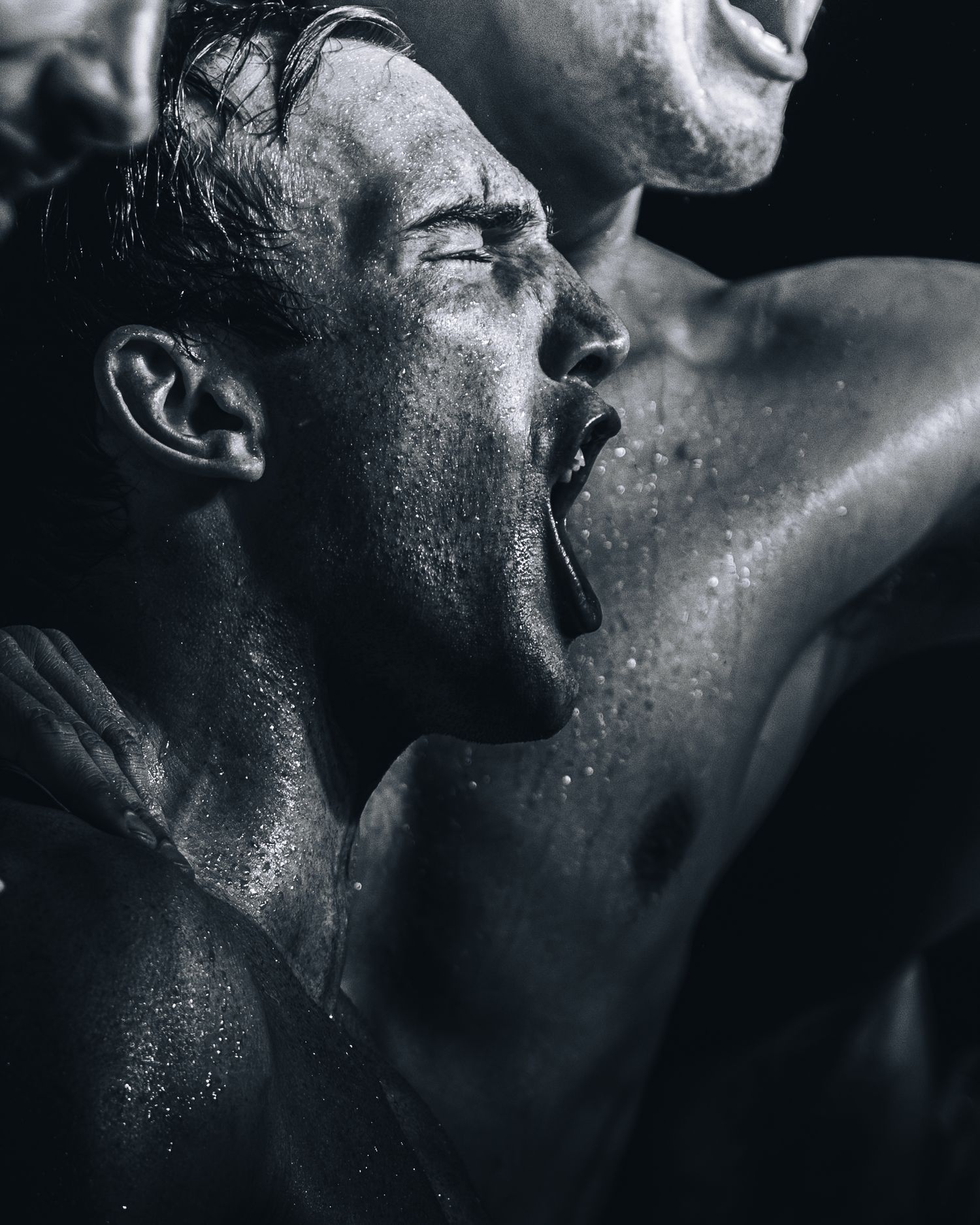 Dramatic black and white close-up of water polo athlete celebrating with water droplets.