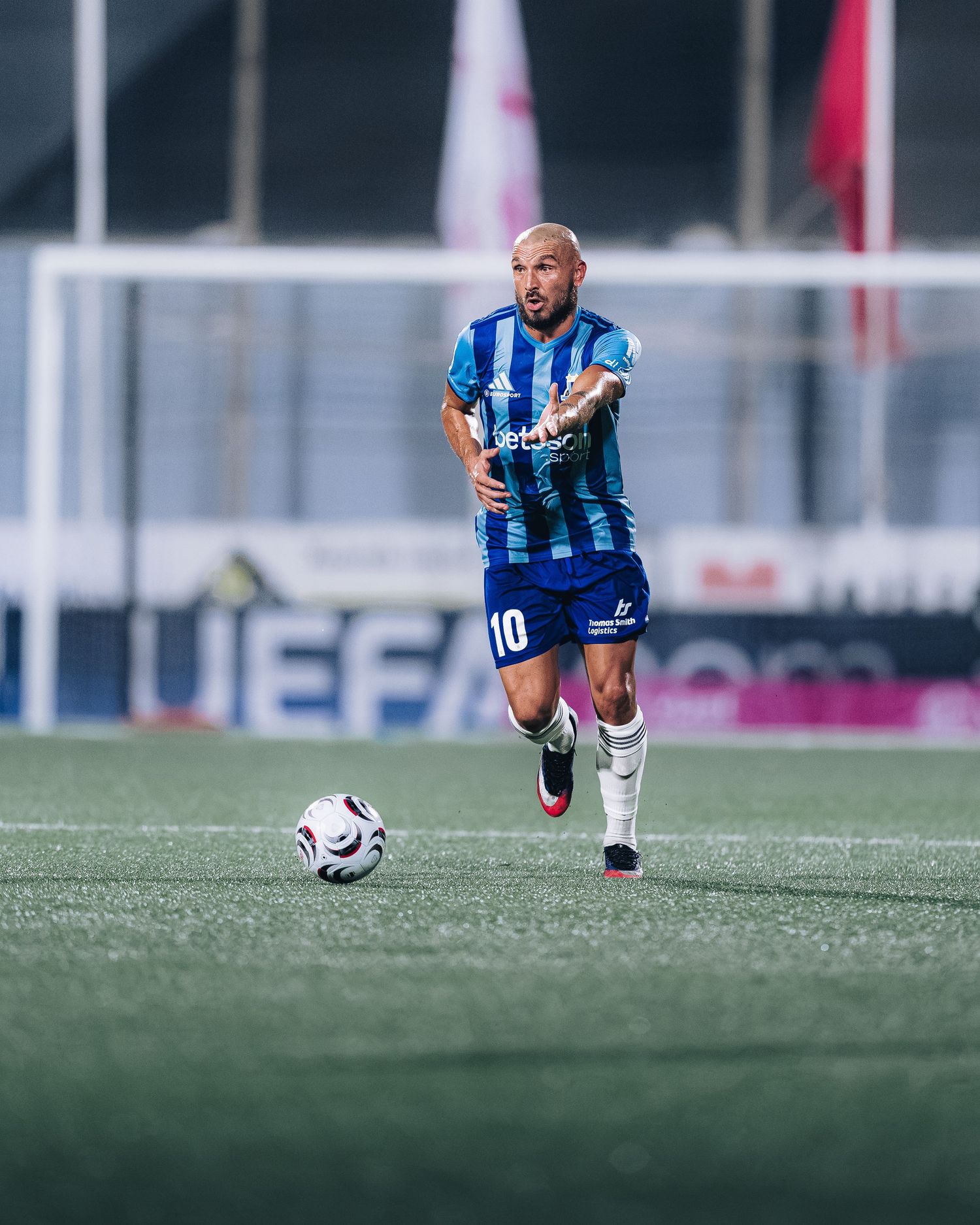 Soccer player wearing number 10 blue kit dribbles ball on field.