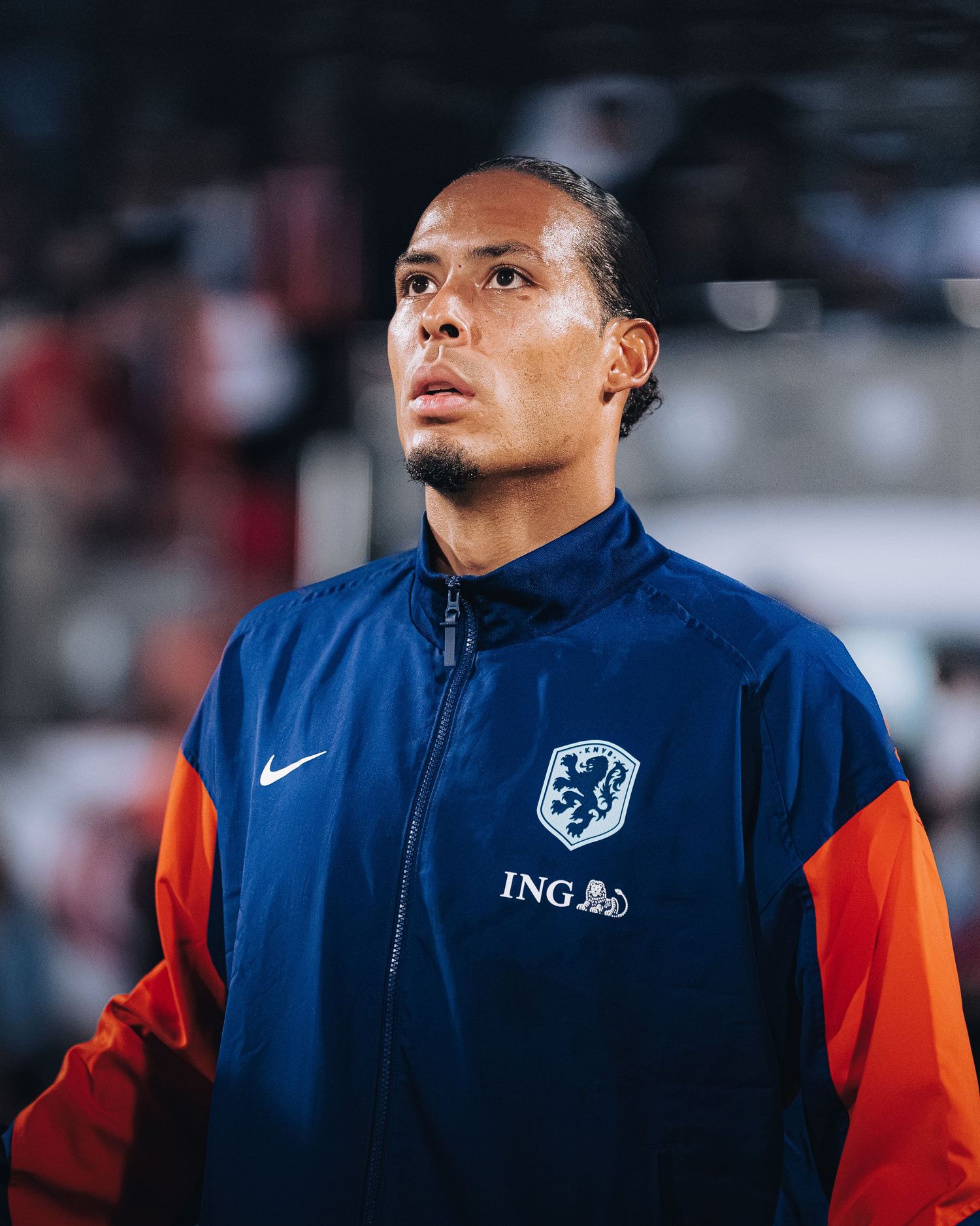 Soccer player in Netherlands blue Nike ING jacket gazes upward before international match.