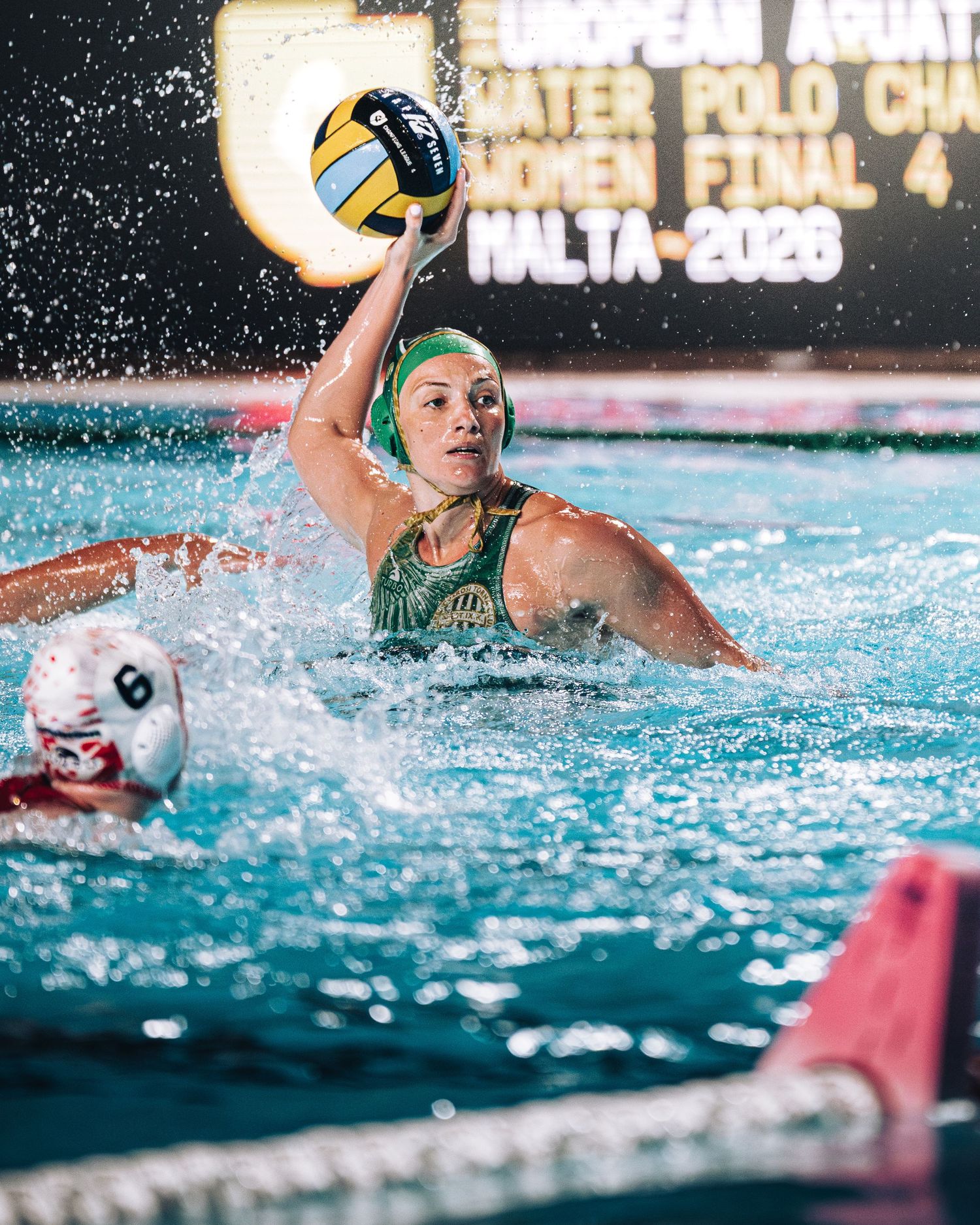 Female water polo player in green cap preparing to throw the ball at European Water Polo Championship Malta 2026.