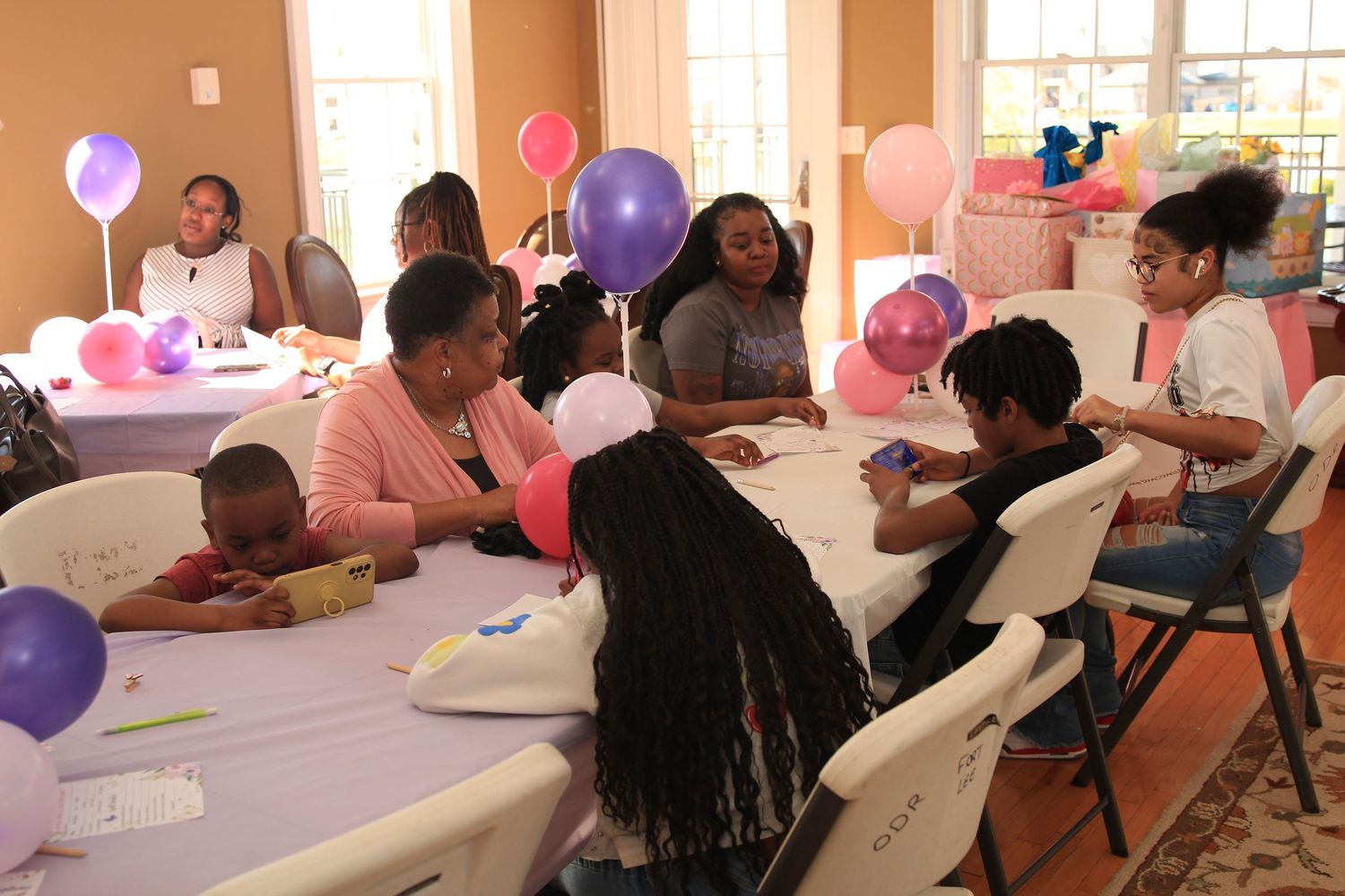 Guests gather around tables decorated with colorful balloons at a festive baby shower celebration.