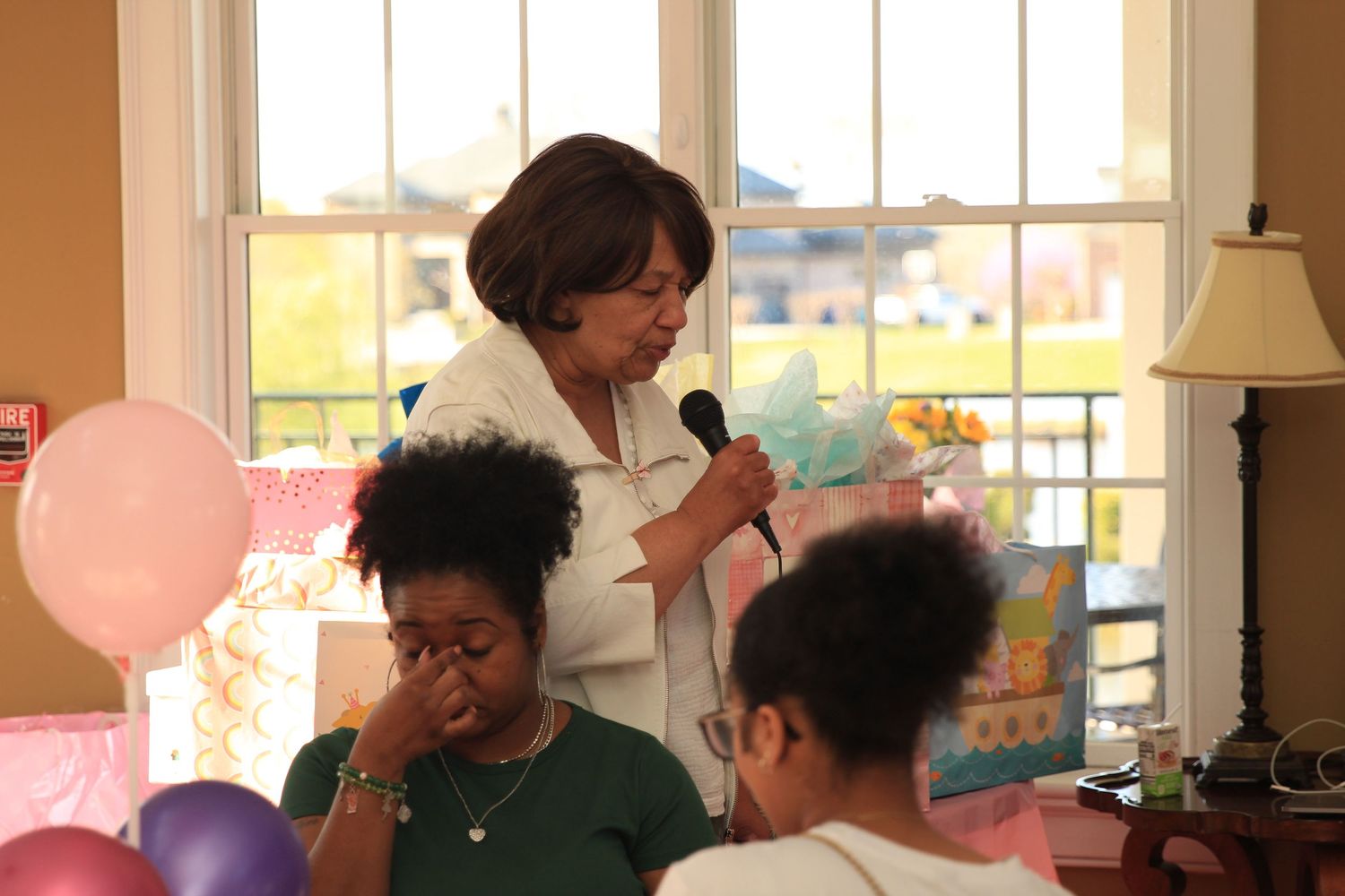 Emotional moment as a woman speaks at a pink and purple baby shower.