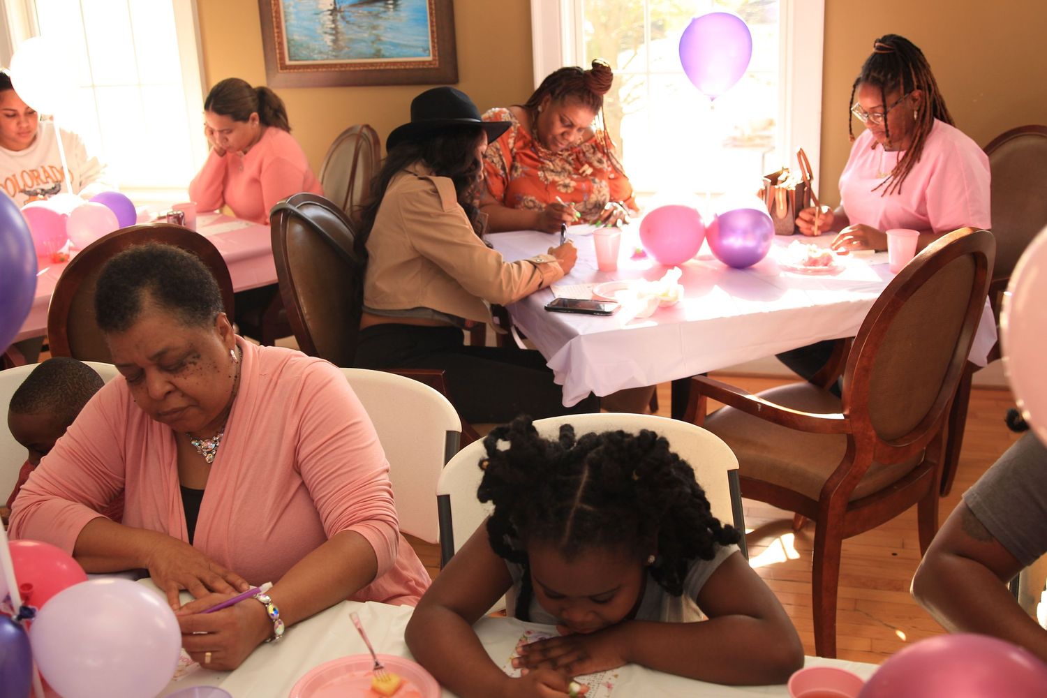 Guests engage in activities at tables adorned with balloons during a baby shower event.