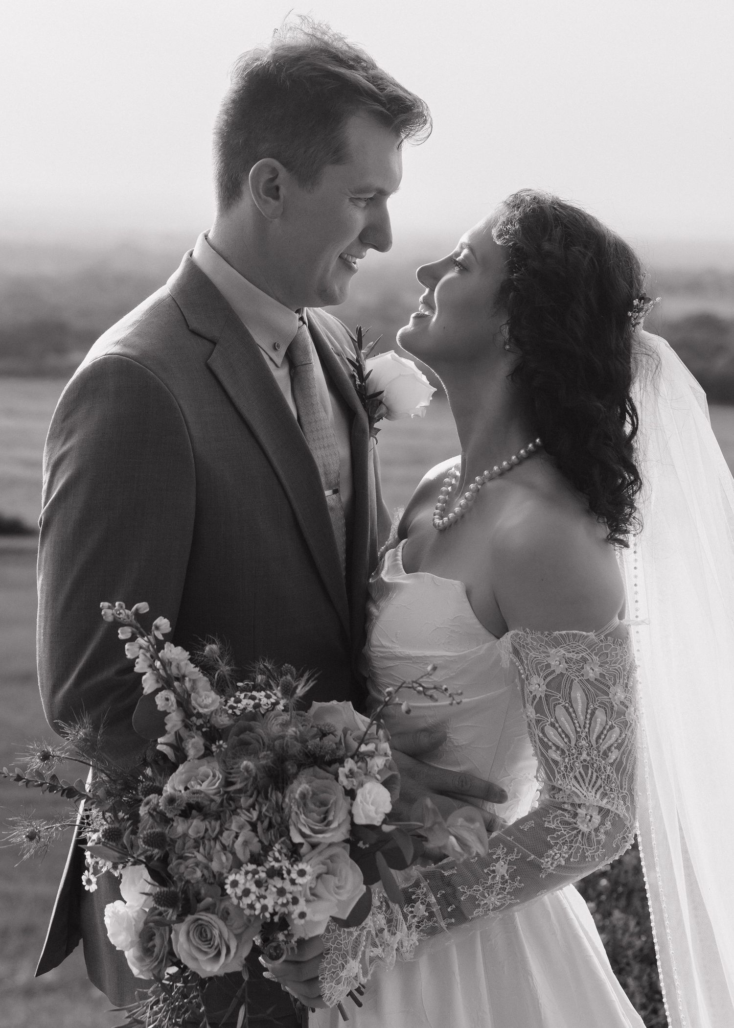 Black and white photo of smiling bride and groom with bouquet.