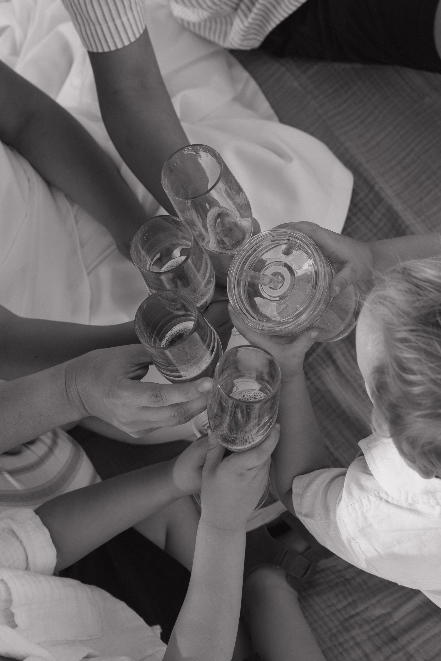 Black and white overhead view of group of people toasting with glasses of water or champagne.