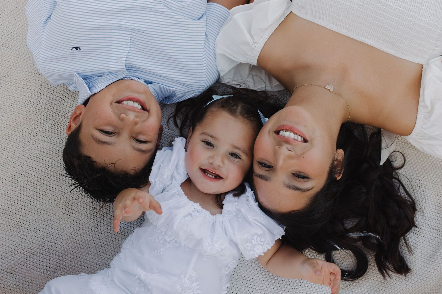 Overhead view of two parents and their toddler lying down smiling together.
