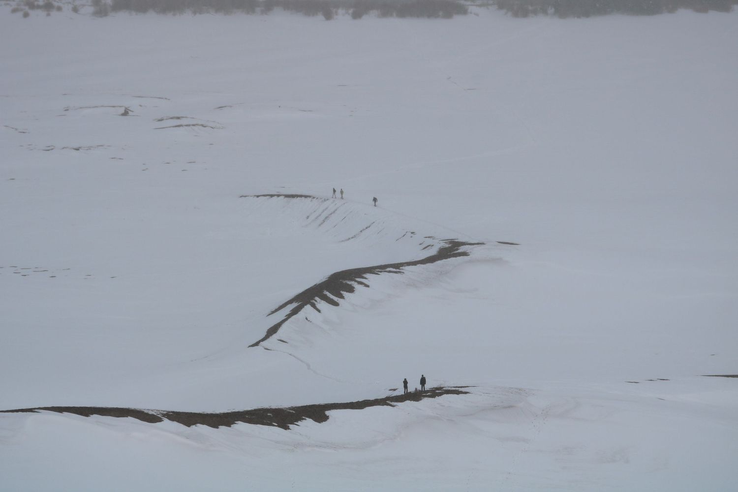 People making their way down the snowy Great Sand Dunes