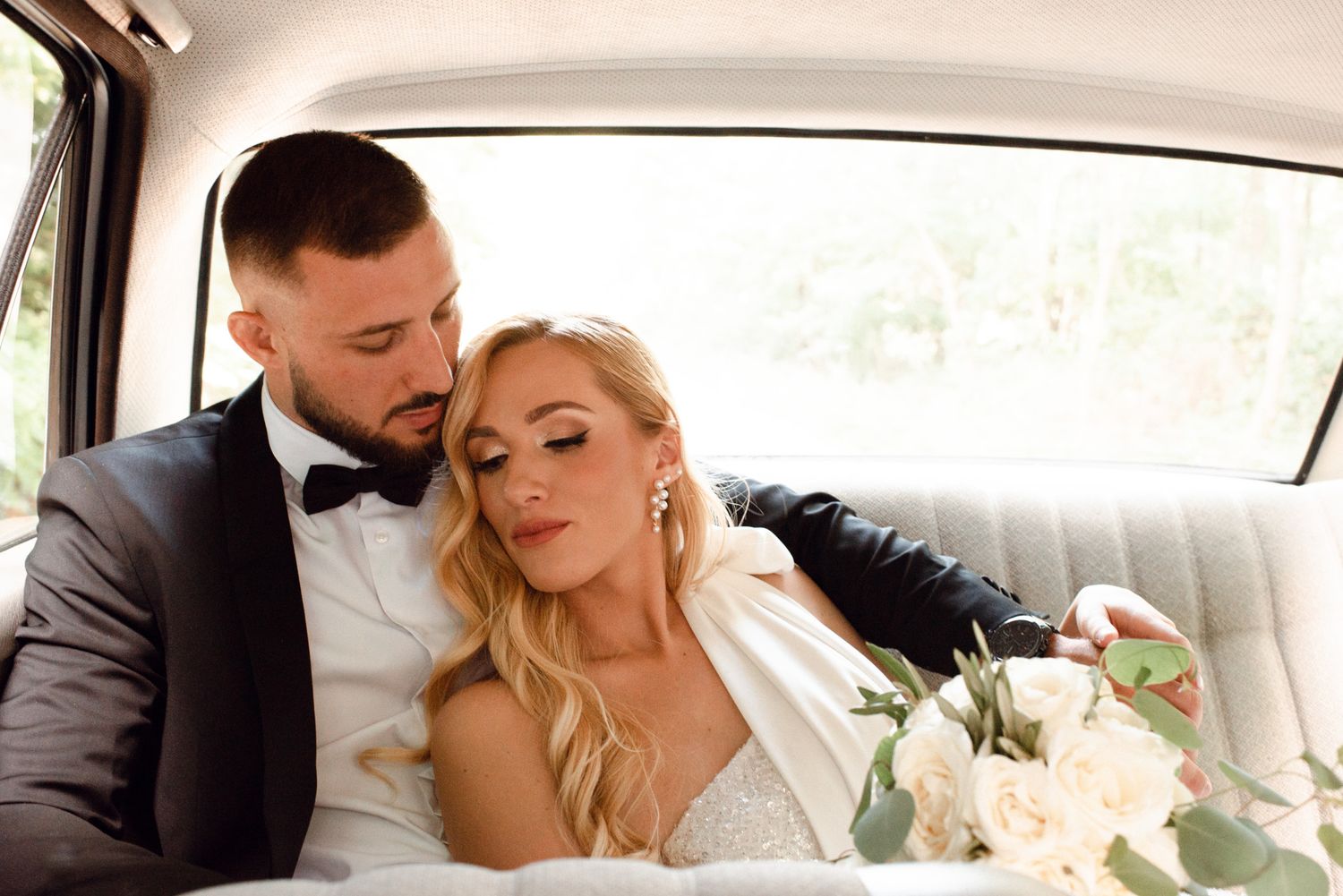 Tender moment between newlyweds in classic car interior.