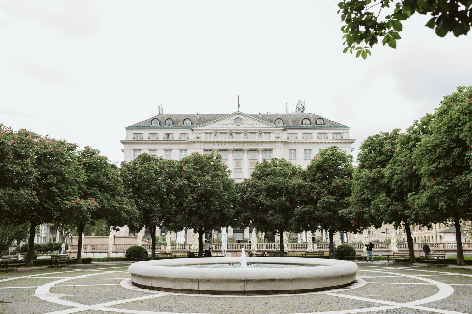Panoramic view of a grand palace and formal gardens with manicured trees.