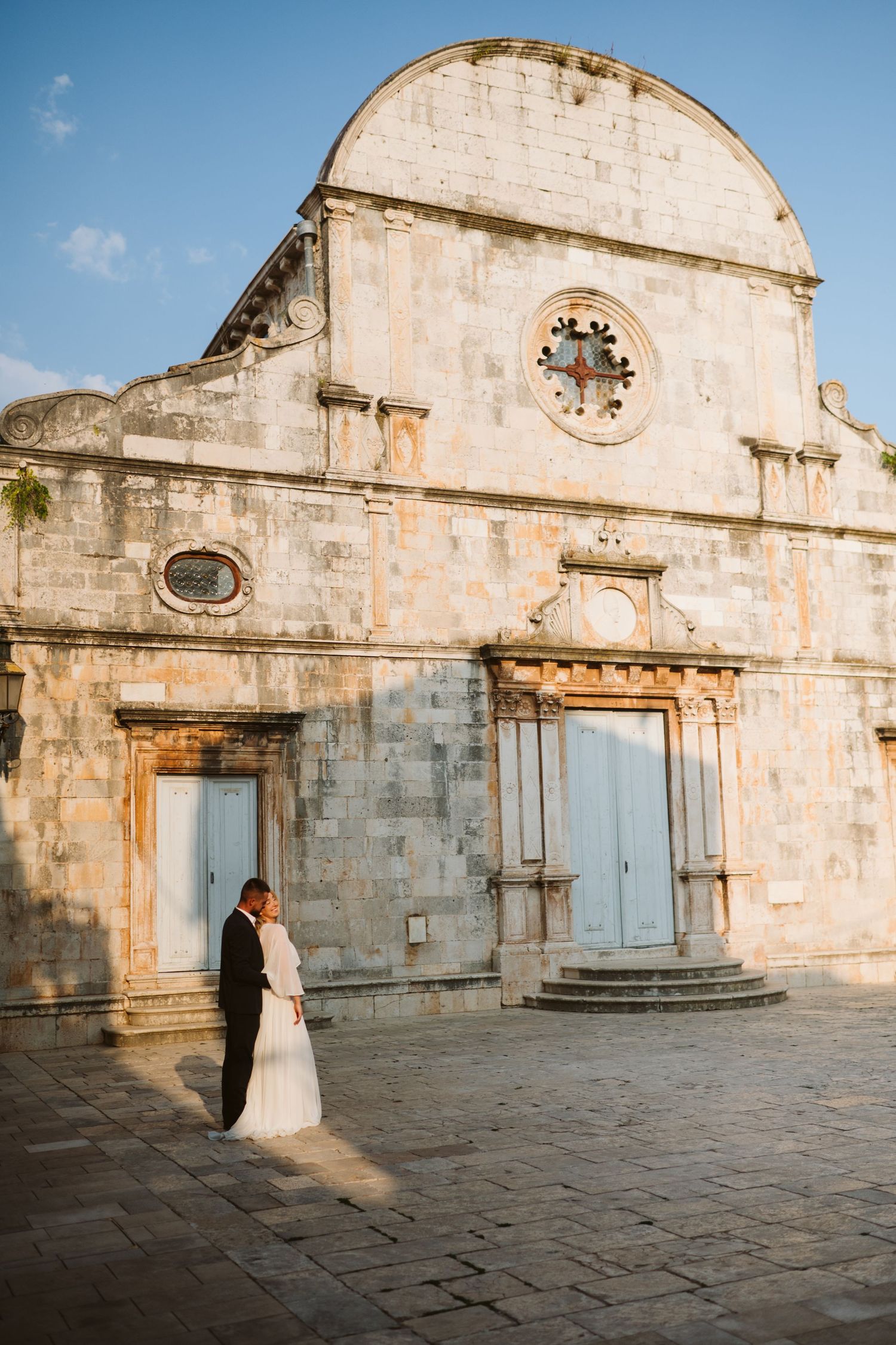 A sequence of wedding photos captured against the historic stone walls of an ancient church courtyard in warm sunlight.
