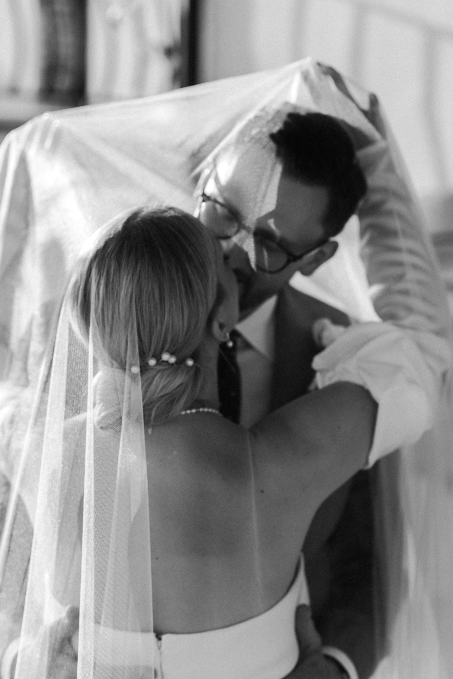 A bride getting her veil adjusted in a black and white photography composition during wedding preparations.