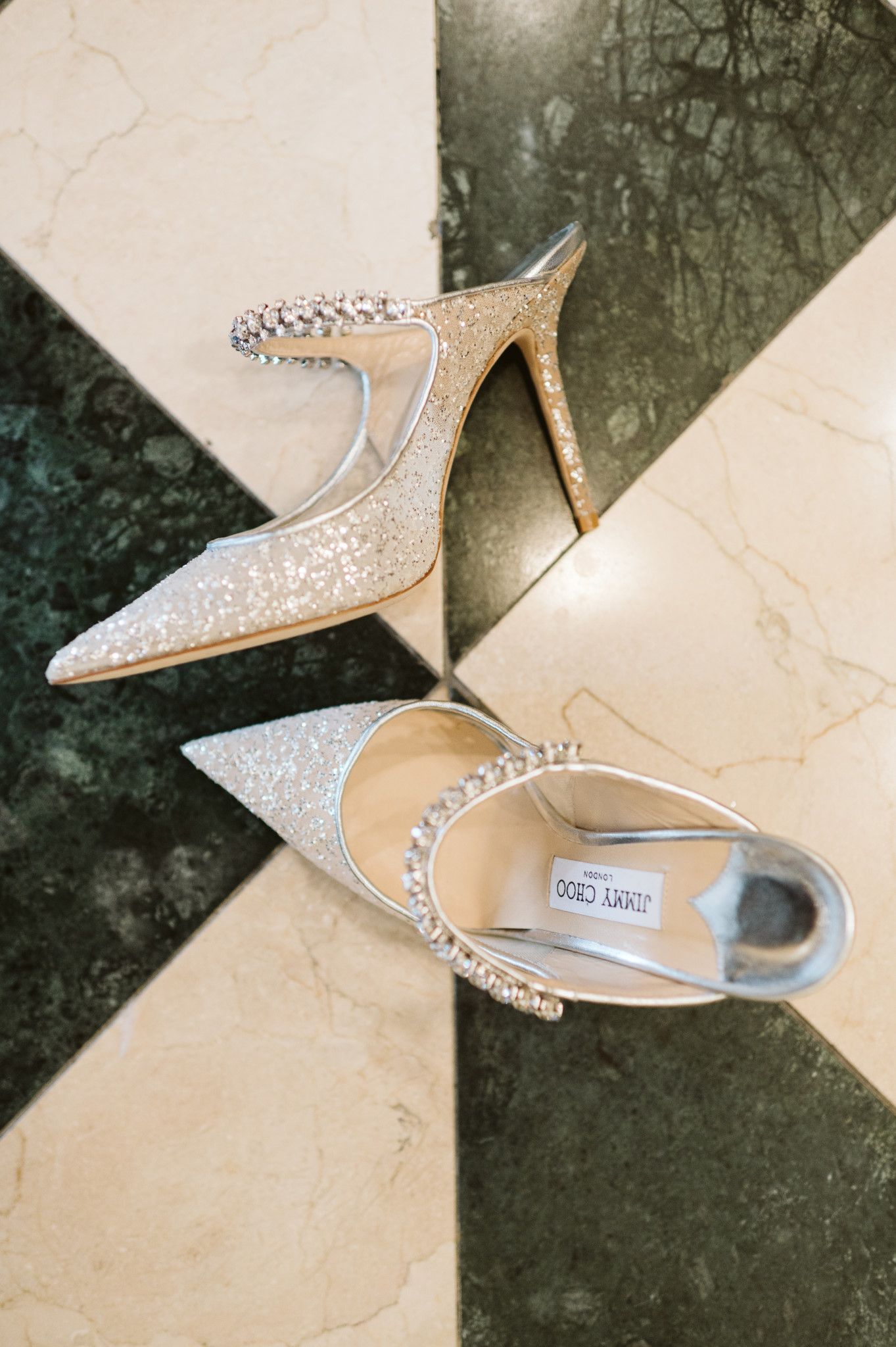 Elegant sparkly bridal shoes with crystal details on a marble surface. Jimmy Choo