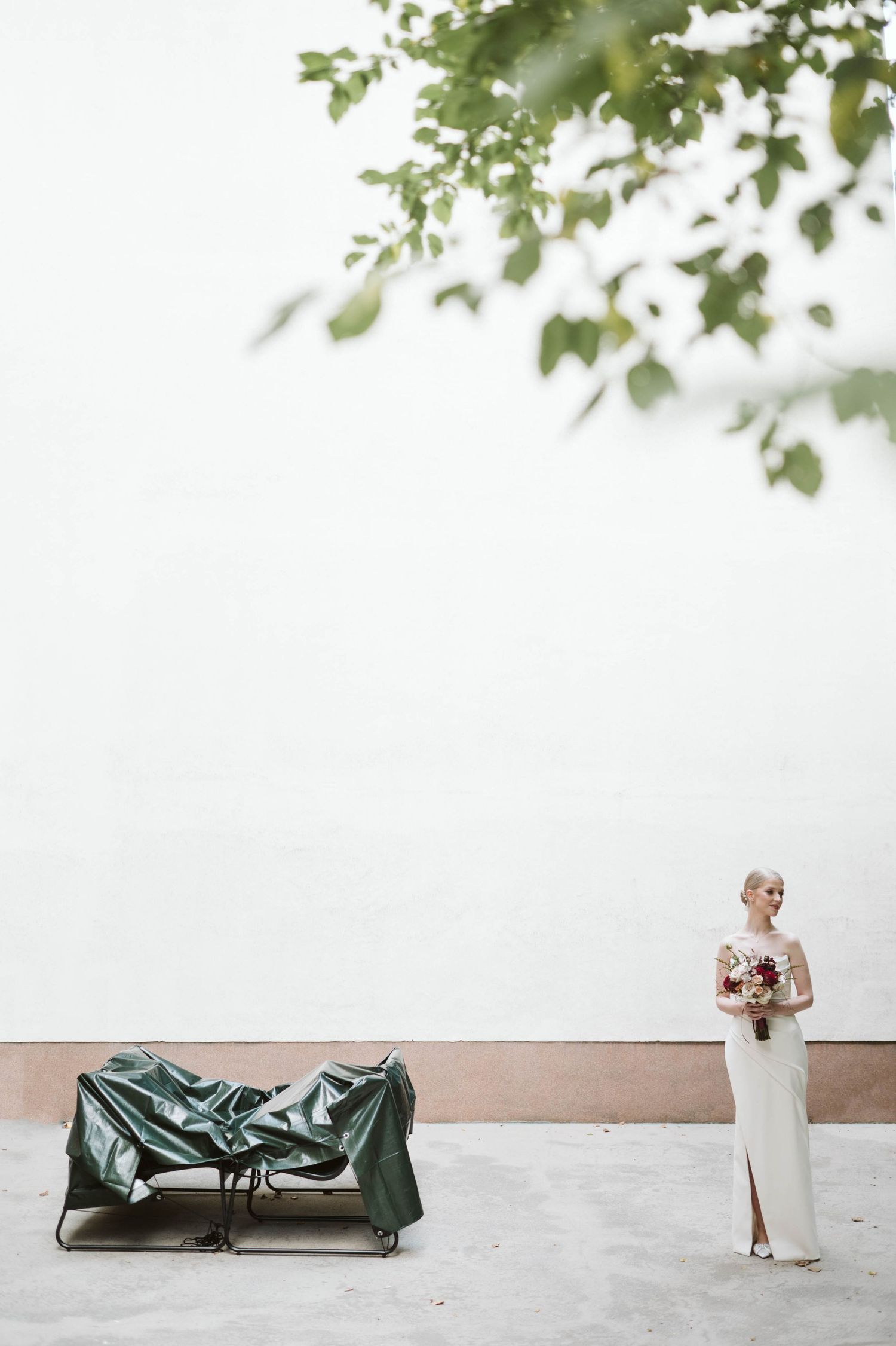 Minimalist wedding ceremony setup with white chairs and green trees creating a natural outdoor backdrop.