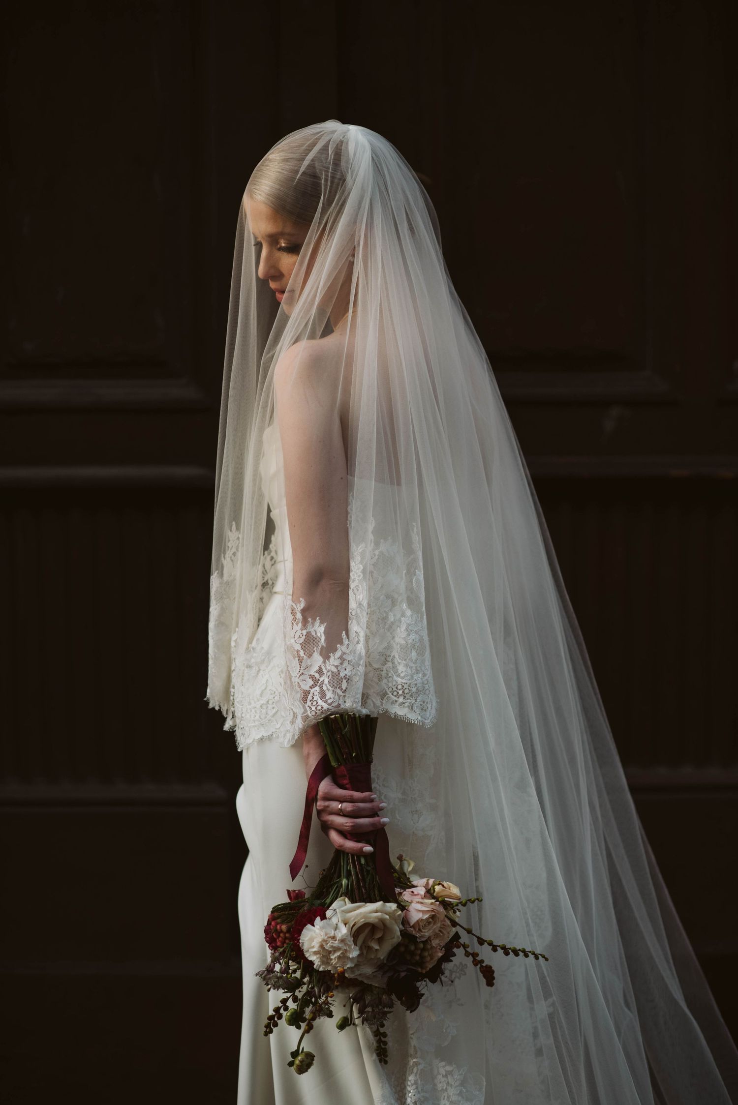A series of moody bridal portraits showing a bride in white lace gown with flowing veil holding a dark burgundy bouquet.