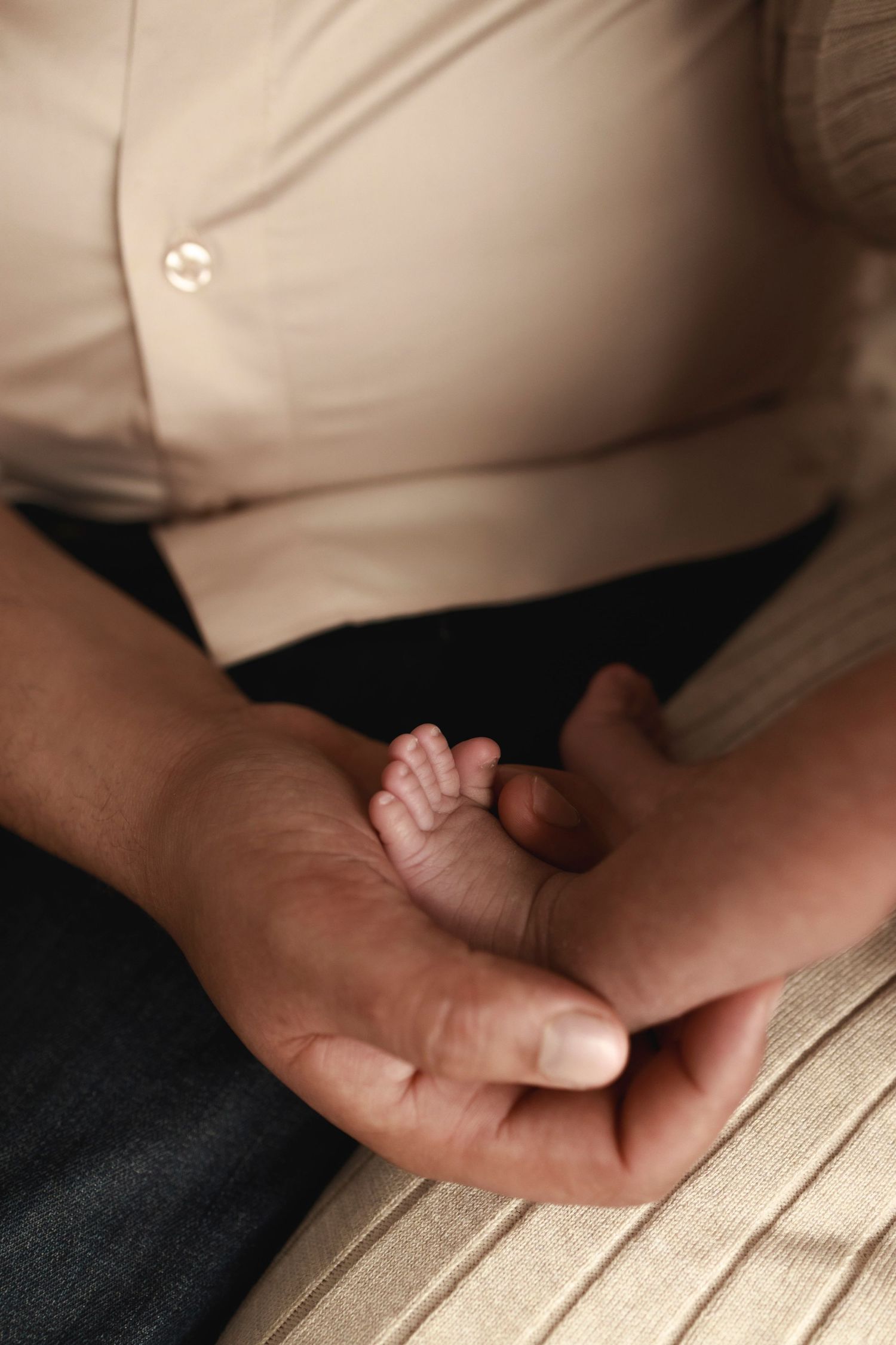 a newborn baby foot being held up in an adult hand with toes pointing towards the light