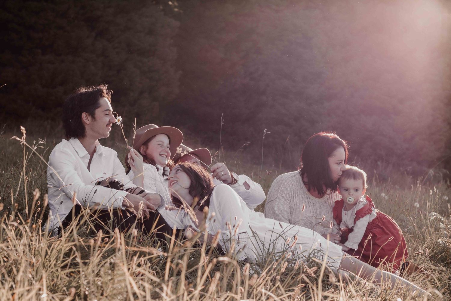 a family sitting together on grass playfully in the sunset light