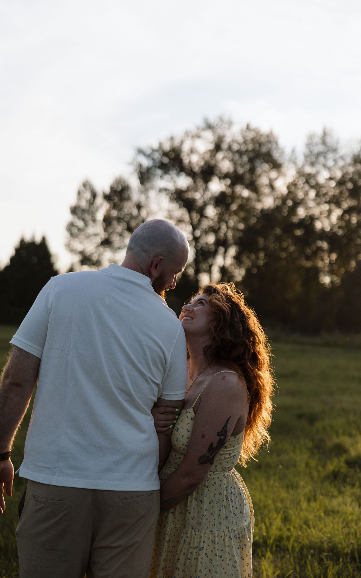 A romantic sunset photoshoot showing a couple embracing in a grassy field in Langley, British Columbia.