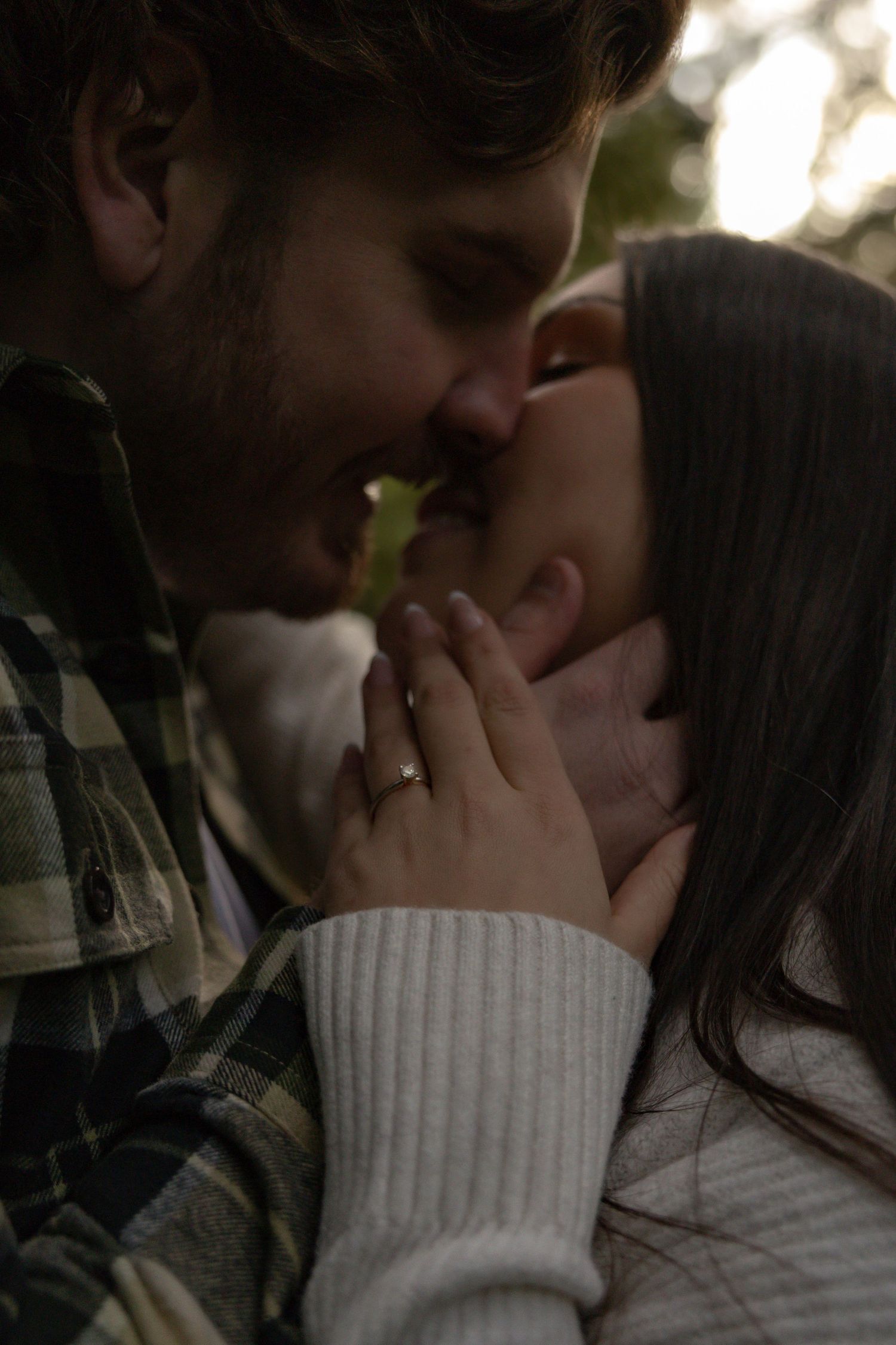 Couple sharing a romantic almost-kiss moment, woman wearing engagement ring, soft moody outdoor lighting, in Maple Ridge, BC
